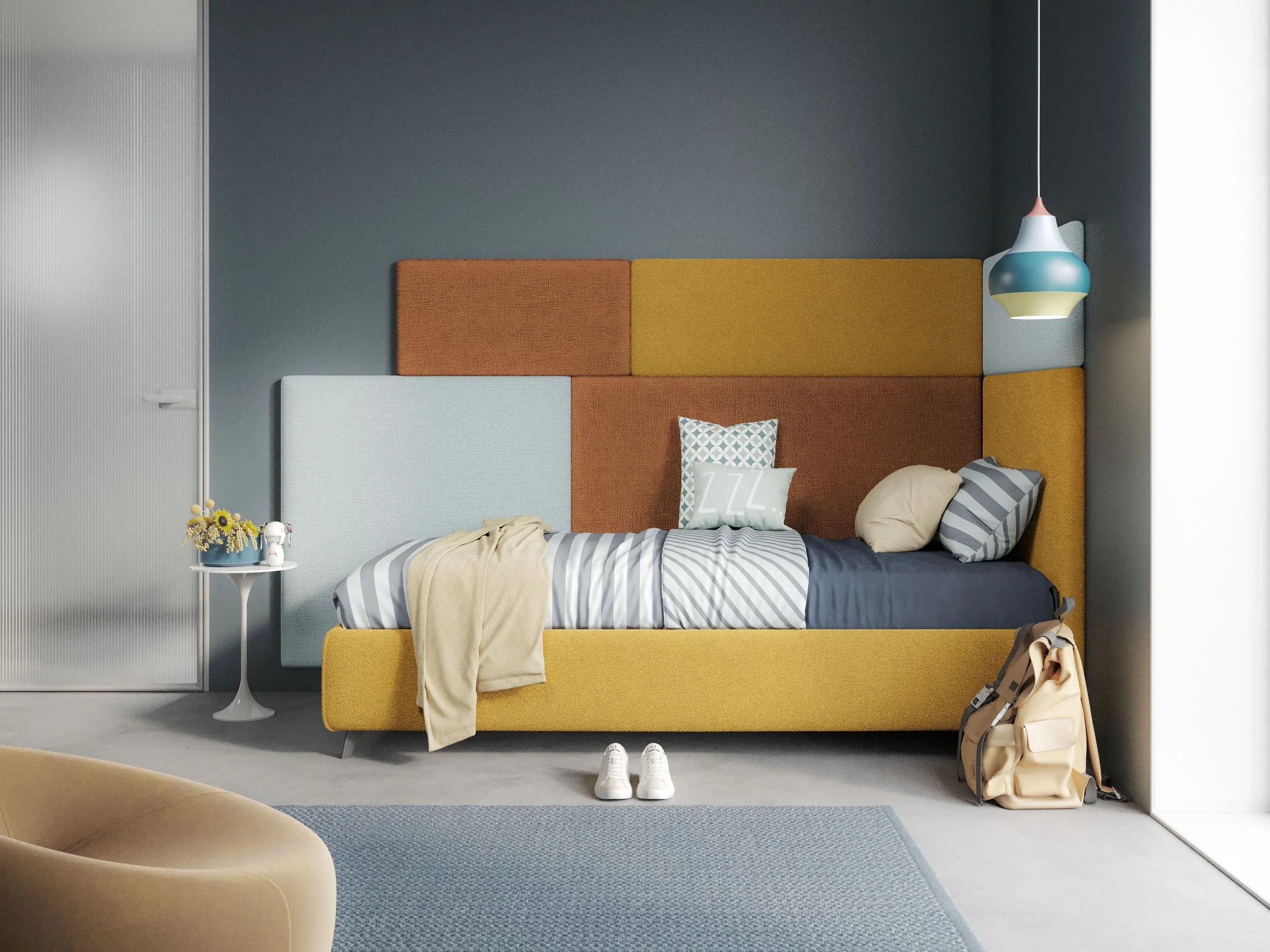 Camera da letto moderna con letto imbottito giallo e marrone, testiera imbottita geometrica, pareti blu, biancheria da letto a righe, cuscini, uno zaino, tavolino rotondo con fiori e una lampada a sospensione blu.