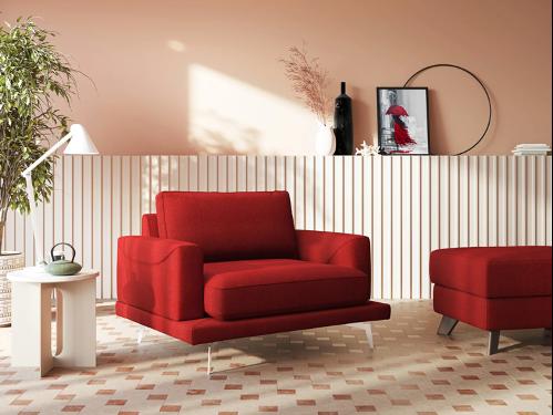 Una donna vestita di nero si rilassa e sorride su una poltrona reclinabile gialla in un soggiorno moderno con pareti verdi, quadri, piante e una scaffalatura sullo sfondo.