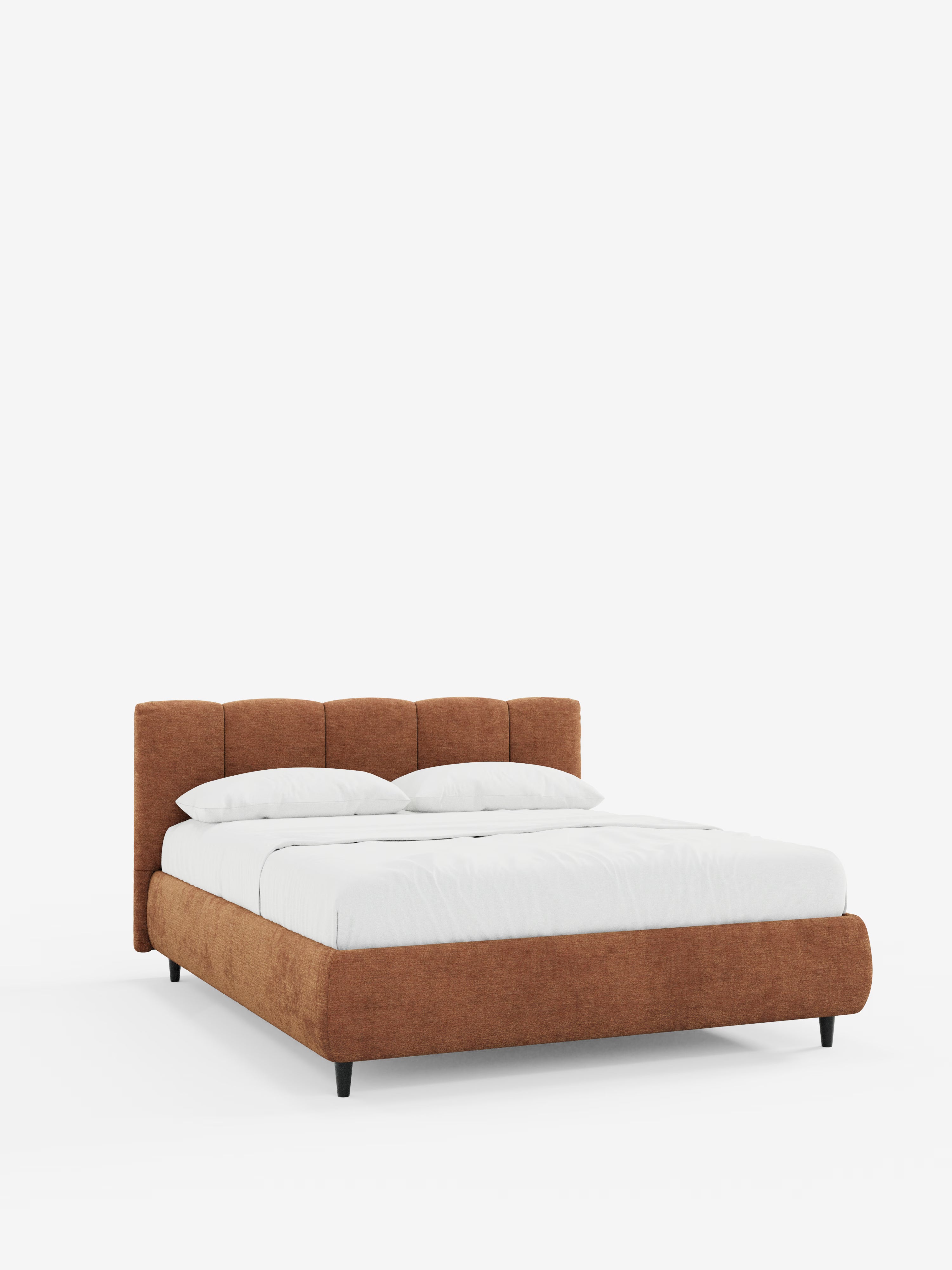Un letto contemporaneo firmato Letti.store: il letto imbottito ARKAM presenta una struttura bassa rivestita in colore ruggine e una testiera imbottita con cuciture verticali in tessuto certificato Oeko-Tex®, dal design shabby chic. Il letto è elegantemente rivestito con biancheria da letto di un bianco candido e due cuscini, il tutto su uno sfondo bianco a tinta unita che mette in risalto le linee pulite e lo stile moderno di questo letto contenitore.