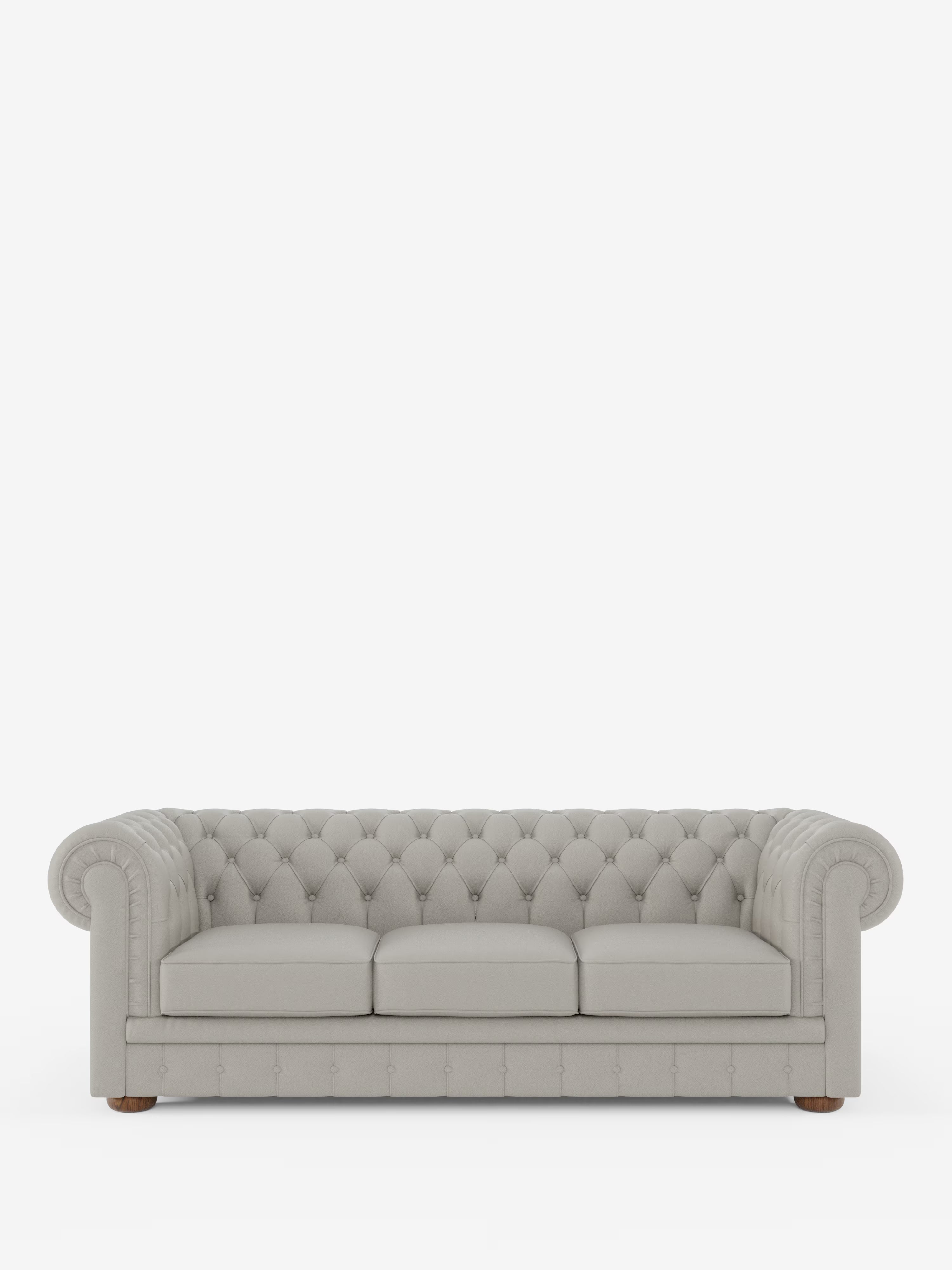 Un divano Chester 4 Posti 3 sedute in vera pelle, di colore grigio chiaro e con rivestimento capitonné – Chesterfield Capitonné Artigianale di Divani.Store, caratterizzato da braccioli arrotondati, tre cuscini di seduta e piedini in legno, è posizionato al centro su uno sfondo bianco a tinta unita, mettendo in risalto la sua rinomata qualità artigianale.