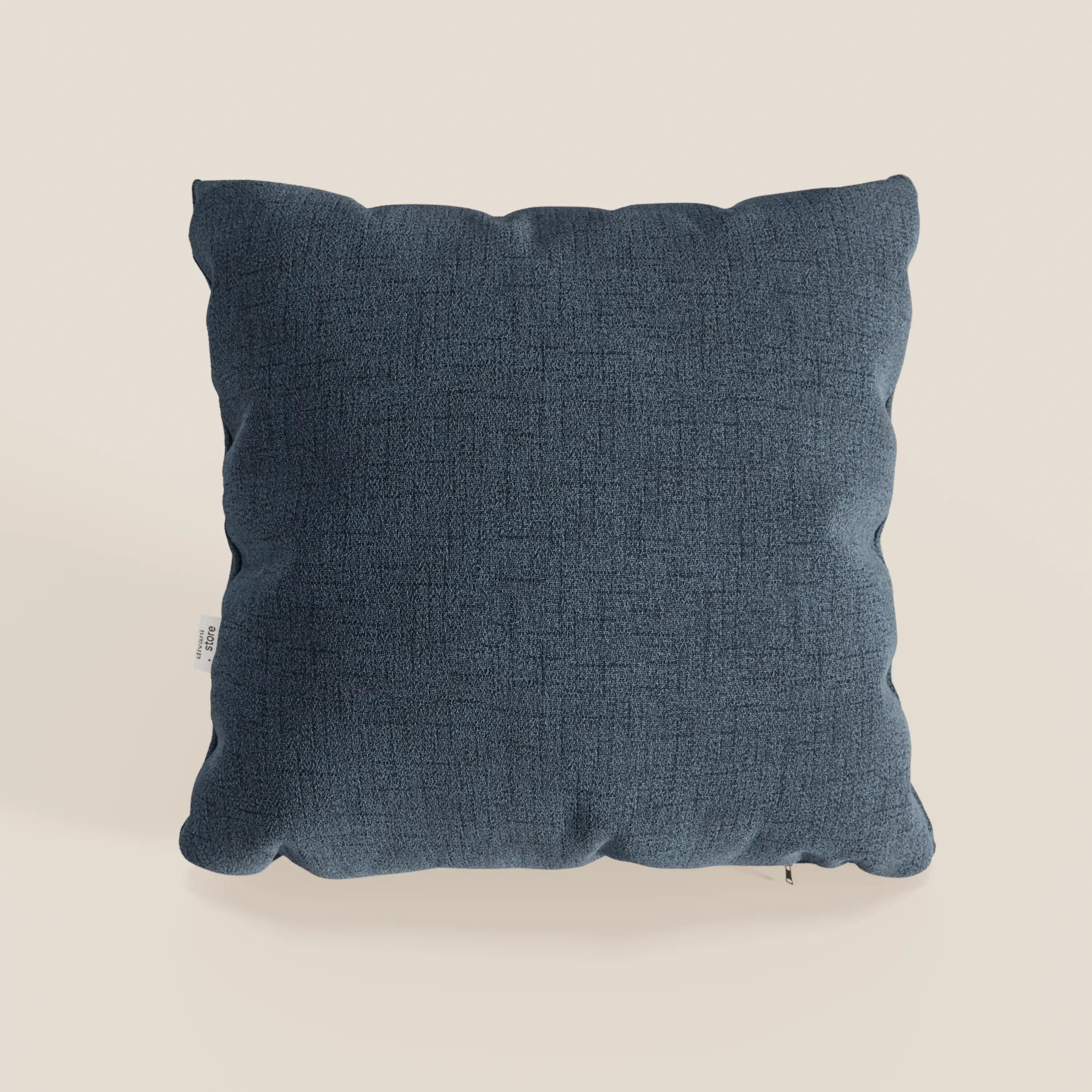 A Felis cuscino impermeabile T03 blu di Divani.Store, in tessuto morbido con superficie testurizzata, è mostrato su sfondo off-white. Un piccolo tag bianco è visibile sul lato sinistro del cuscino quadrato.