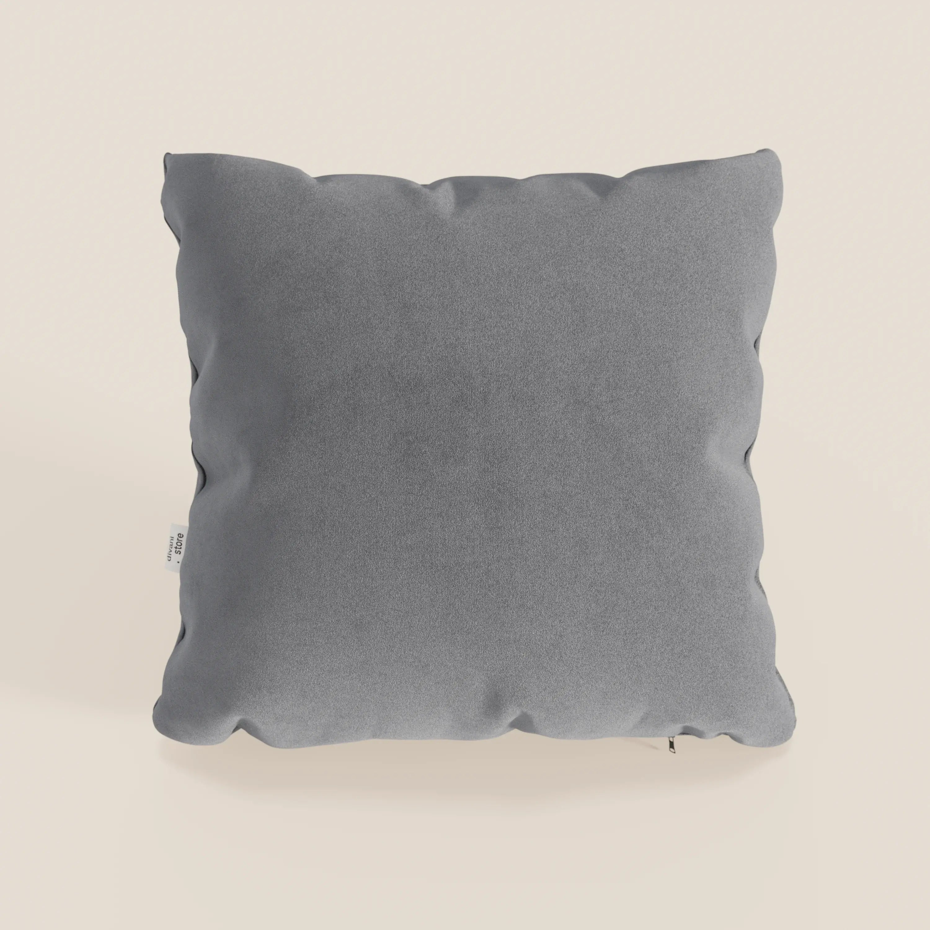 Il cuscino Jazz di Divani.Store, presentato in T11 grigio, ha una forma quadrata, un rivestimento in morbida microfibra tecnica antimacchia, cuciture sottili, angoli arrotondati e una piccola etichetta bianca su uno sfondo bianco sporco.