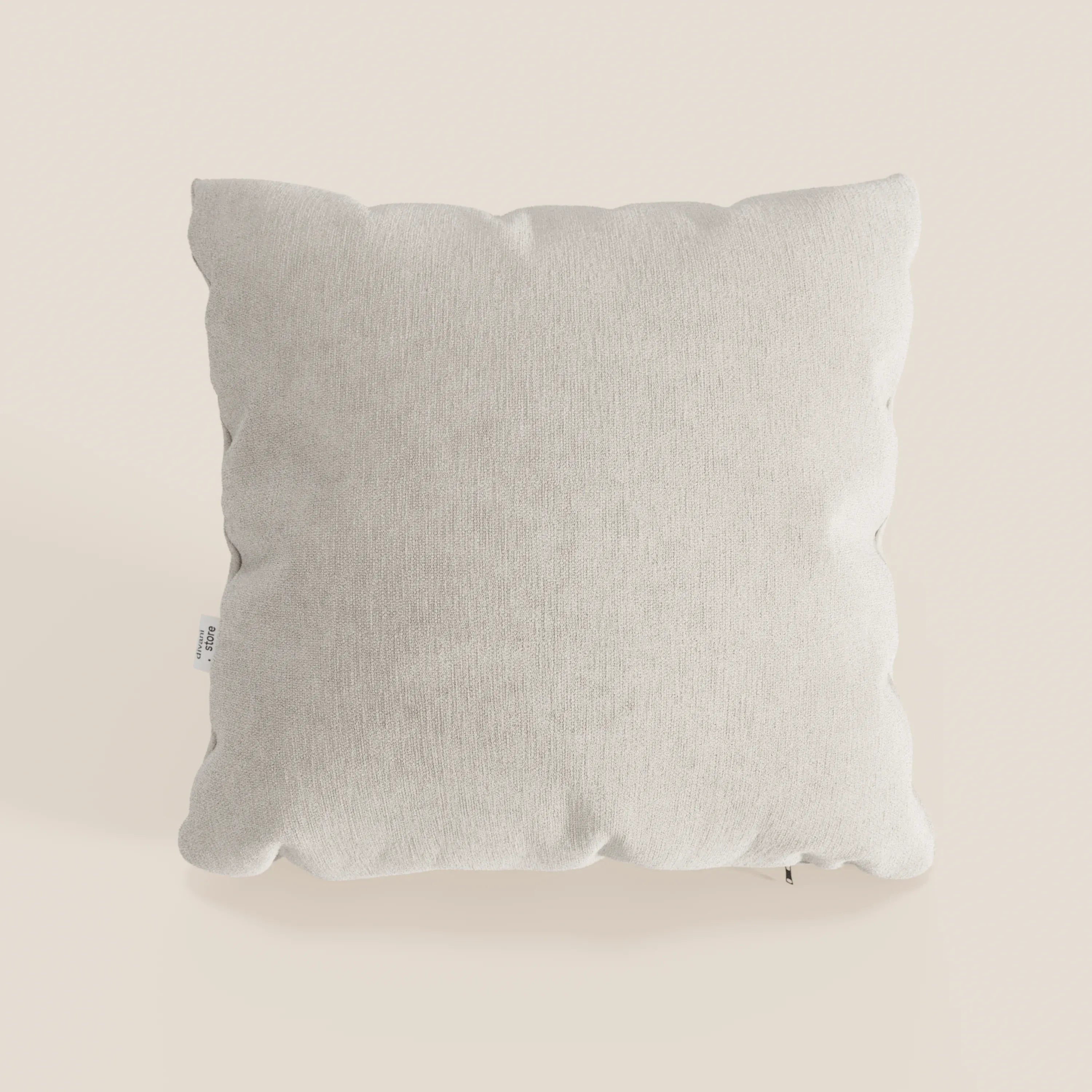 Il cuscino Bolero di Divani.Store è un cuscino quadrato di colore grigio chiaro in morbido tessuto T31 antimacchia, impermeabile e non restringente. Presenta una texture sottile, angoli smussati e una piccola etichetta bianca sul lato sinistro.