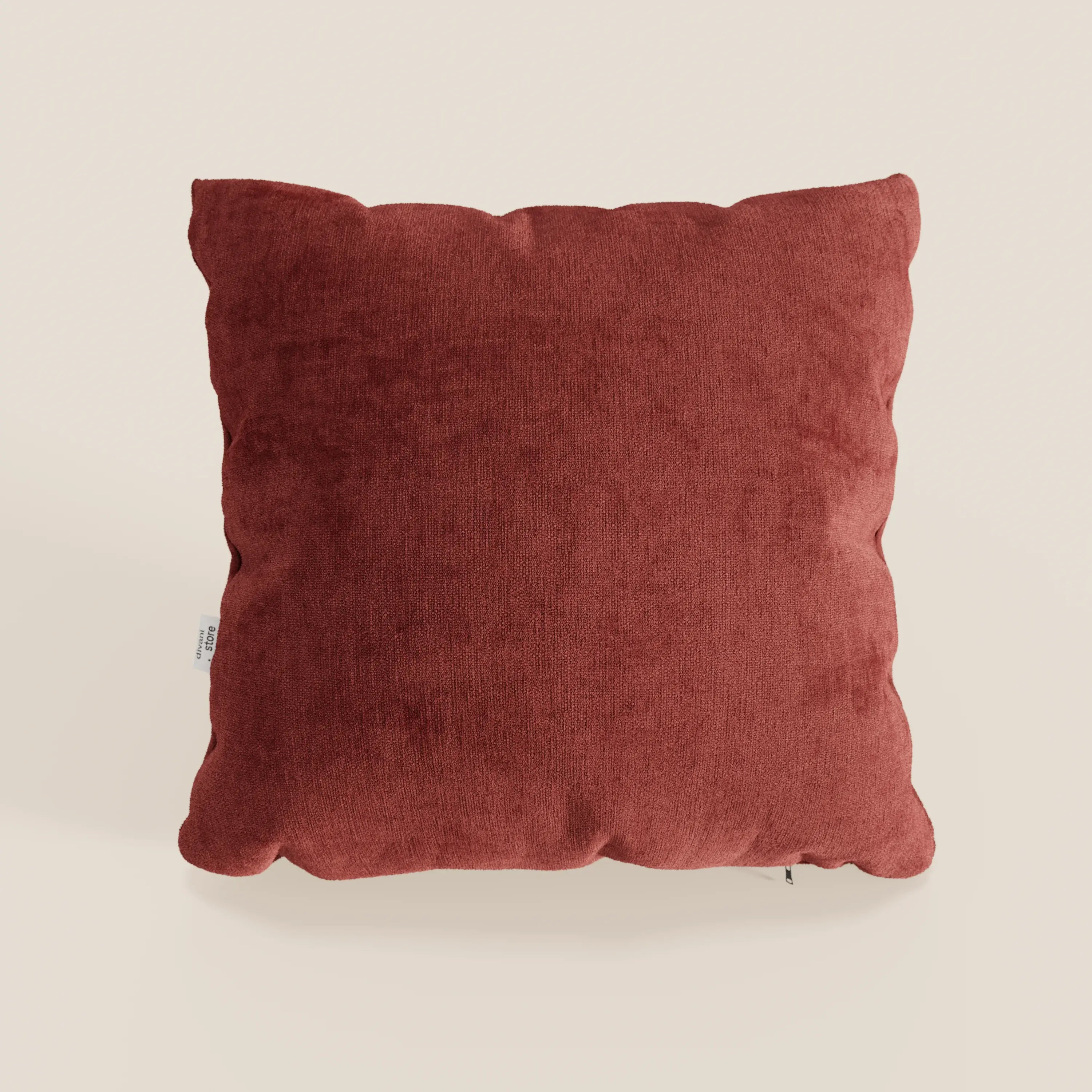 Il cuscino Bolero di Divani.Store, di colore rosso ruggine, è caratterizzato da un design quadrato e felpato, con un tessuto T31 morbido, antimacchia, impermeabile e non restringente. Ha angoli leggermente arrotondati e una piccola etichetta bianca sul bordo sinistro.