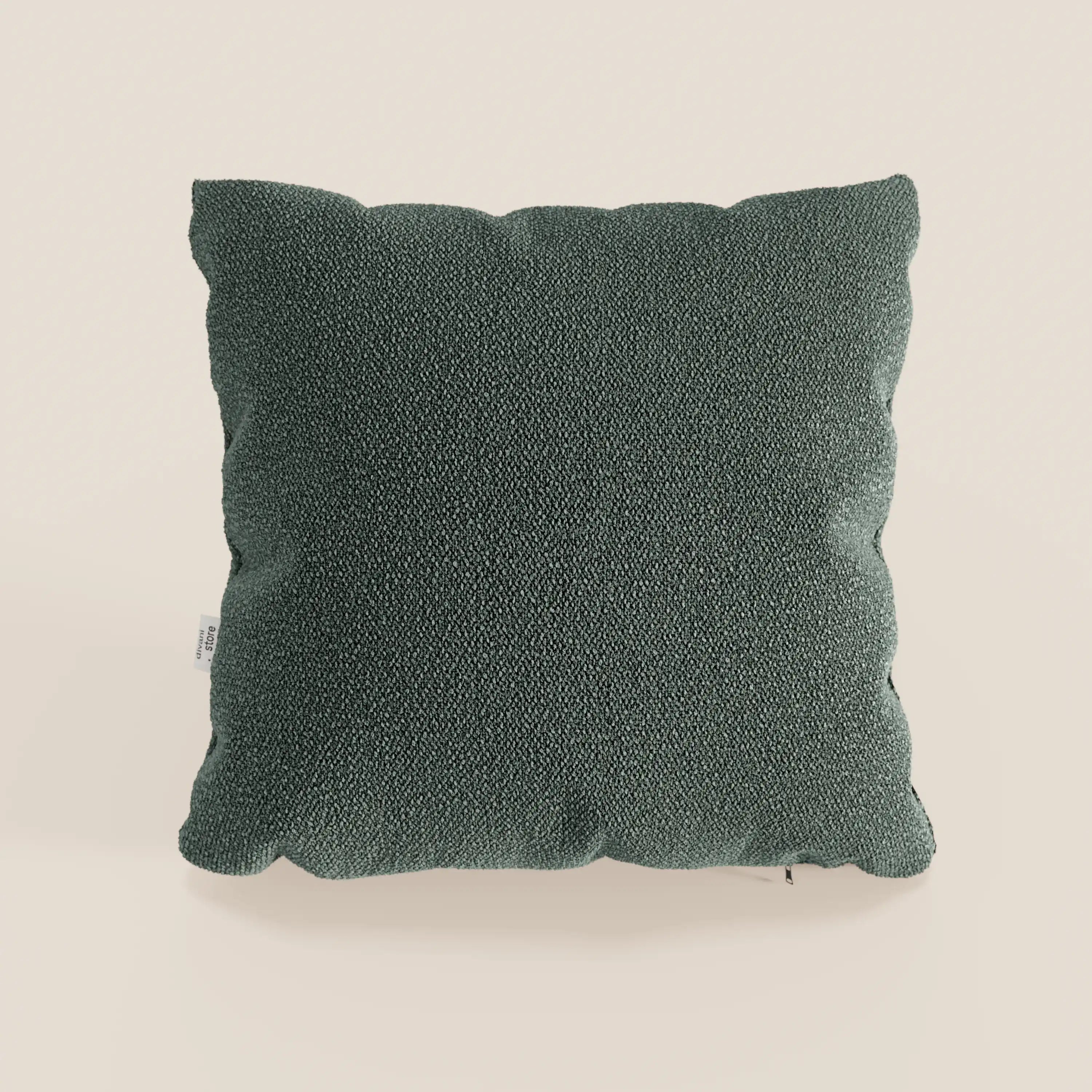 Il cuscino Lambada di Divani.Store, di forma quadrata e di colore verde scuro, realizzato in tessuto smacchiabile e impermeabile effetto cotone naturale, si presenta con bordi leggermente arrotondati e una piccola etichetta bianca a sinistra su uno sfondo beige chiaro.