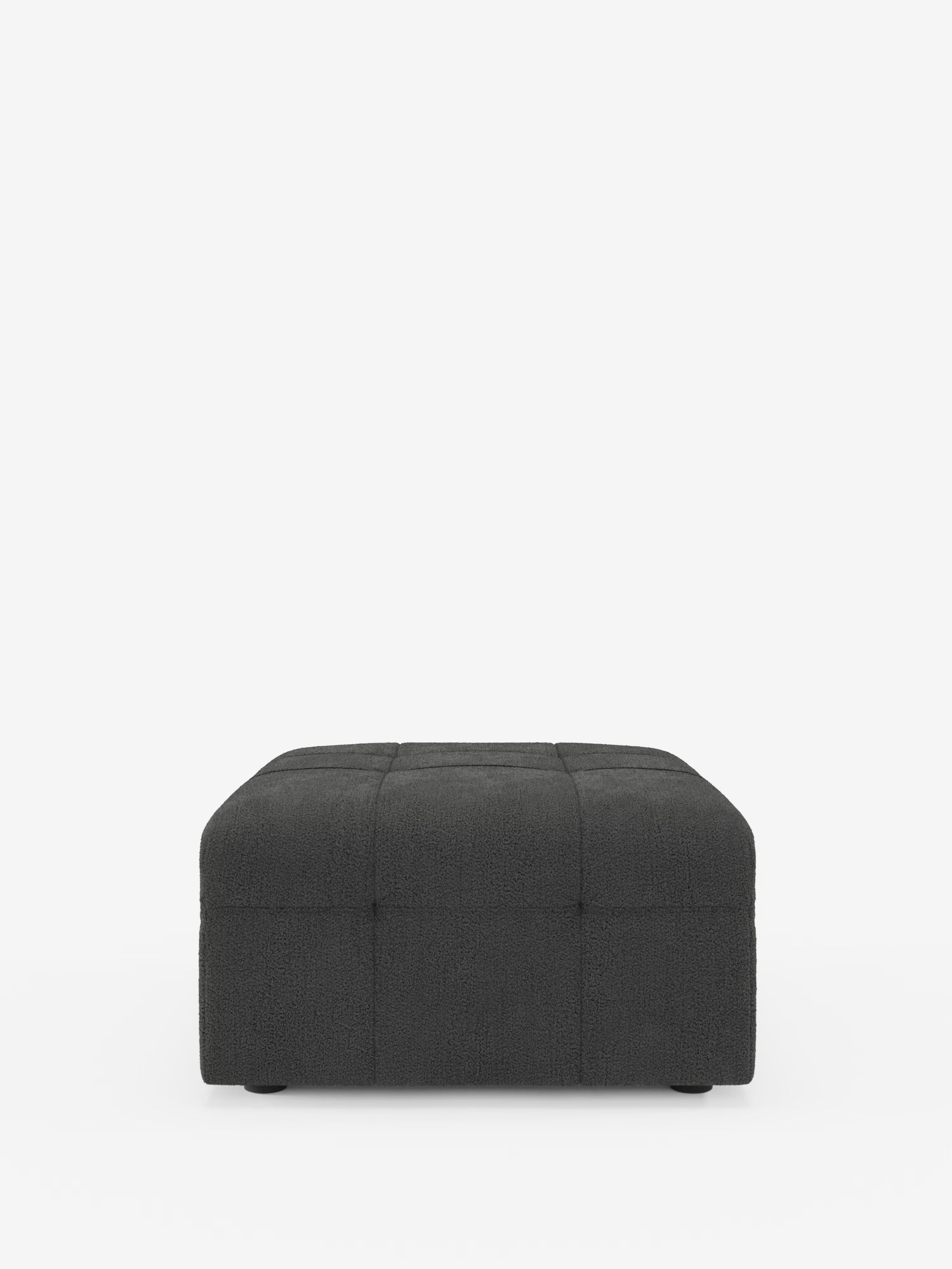 Un pouf quadrato imbottito di colore grigio scuro di Divani.Store — in particolare il pouf e modulo Mosaic in bouclé, 96x77 cm con motivo capitonné in tessuto T21 antimacchia — presenta un motivo a griglia trapuntato sui lati e sulla parte superiore, il tutto su uno sfondo bianco. Il pouf è basso e moderno, con gambe corte e quasi invisibili che ne completano l’estetica contemporanea.