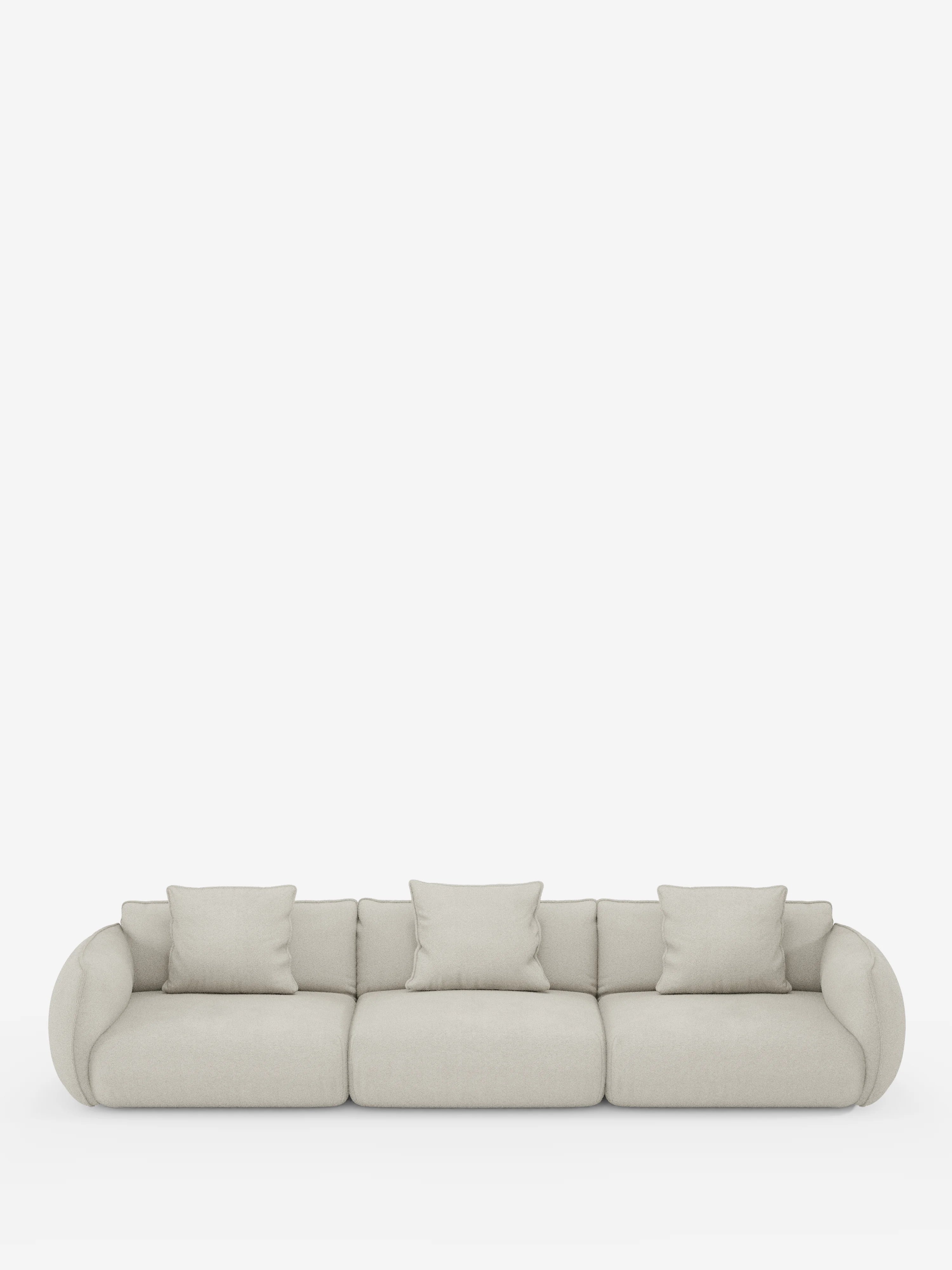 Un moderno divano modulare a 3 posti Nimbus di Divani.Store, rivestito in morbido tessuto T33 effetto cotone, resistente alle macchie, in beige chiaro. Questo divano presenta tre ampi cuscini di seduta, cinque cuscini coordinati, braccioli arrotondati e uno schienale basso, il tutto messo in risalto da uno sfondo bianco a tinta unita che esalta il suo design minimalista e versatile.