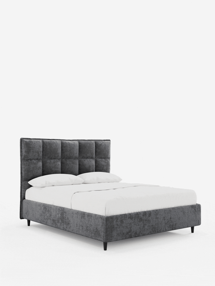 Un letto imbottito AURO grigio con contenitore e testiera alta capitonné in ciniglia Oeko-Tex®, caratterizzato da una testiera alta con trapuntatura a griglia, con biancheria da letto bianca immacolata, su gambe corte e affusolate di colore scuro, su uno sfondo bianco a tinta unita.