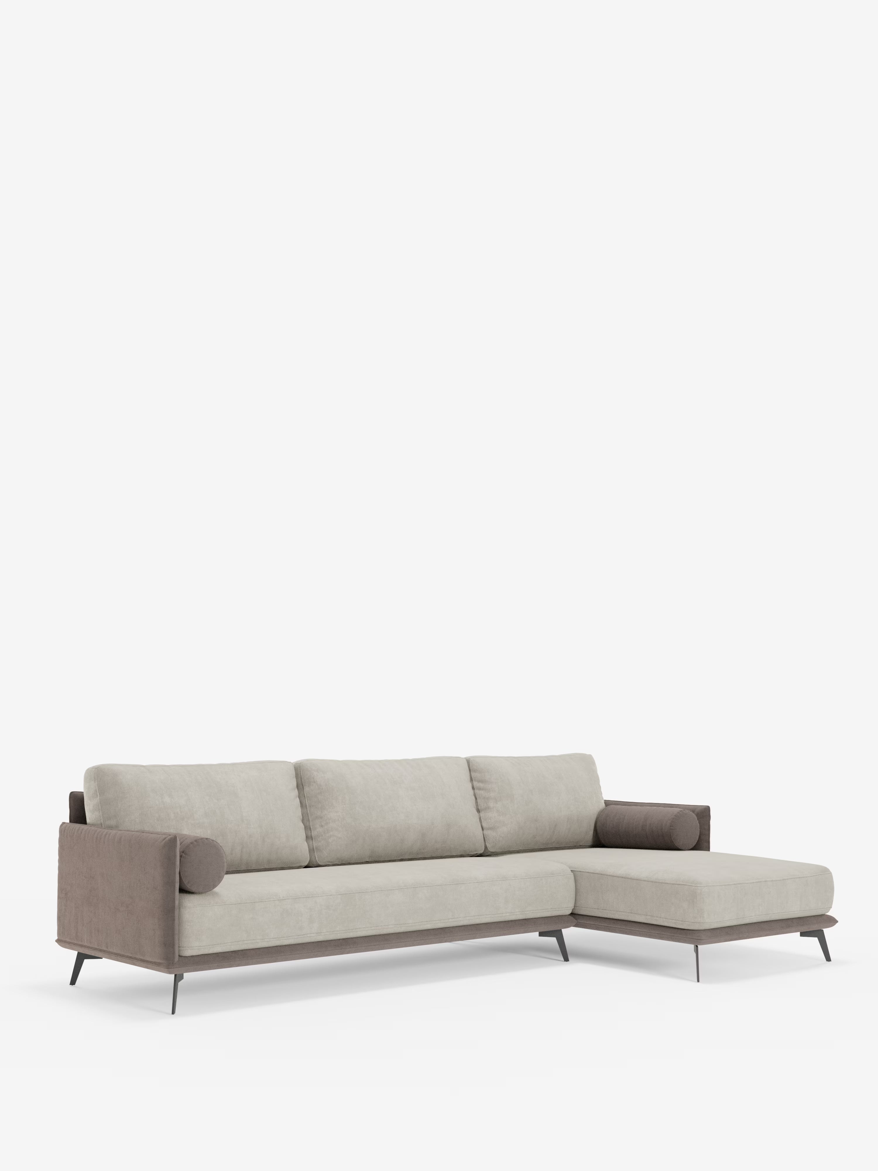 Il divano angolare bicolore Basalto di Divani.Store presenta una penisola con chaise longue allungata sul lato destro, cuscini in tessuto T31 grigio chiaro morbido al tatto e resistente alle macchie con schienali imbottiti in piuma, braccioli e base rivestiti in marrone scuro a contrasto, cuscini cilindrici alle due estremità e sottili gambe angolate in metallo scuro. Lo sfondo è bianco a tinta unita.
