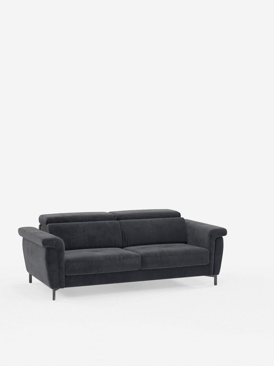 Un divano letto Capri di design contemporaneo, color grigio scuro, realizzato da Divani.Store, dotato di due cuscini di seduta, due cuscini dello schienale, ampi braccioli e gambe alte e slanciate in metallo nero, con poggiatesta regolabili rivestiti in un elegante tessuto effetto velluto antimacchia (T30), che risalta su uno sfondo bianco a tinta unita.