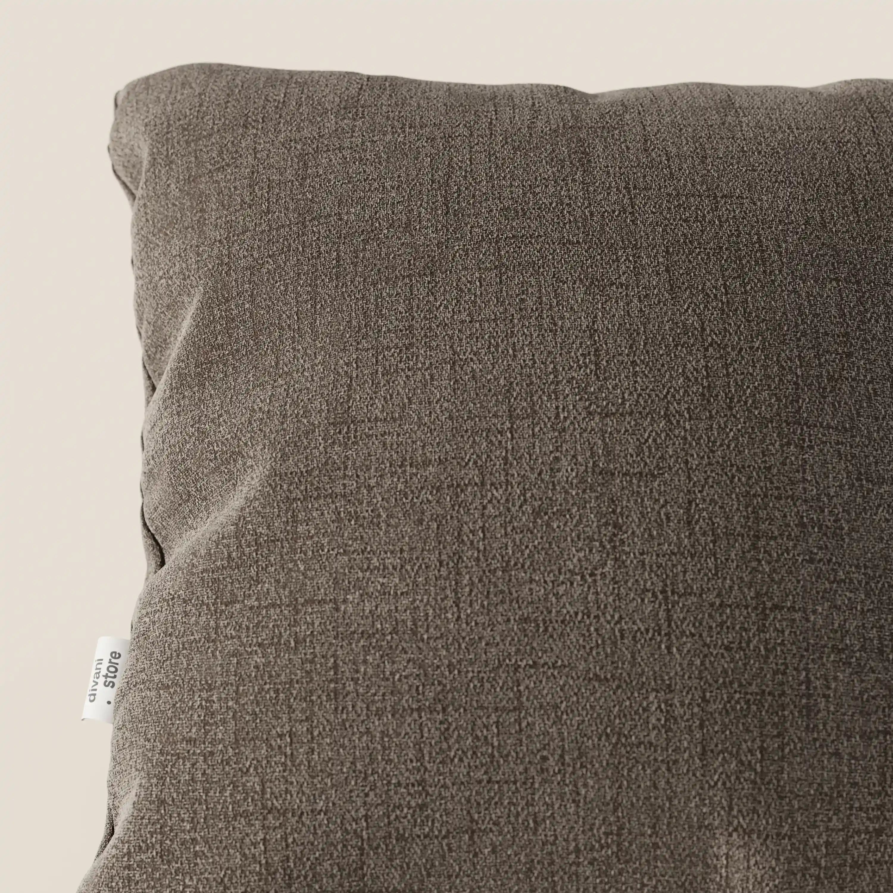 Un primo piano di Felis cuscini di Divani.Store, nella tonalità T03 marrone. Il cuscino quadrato, impermeabile, presenta una sottile trama con una piccola etichetta bianca sul lato, su uno sfondo beige chiaro.