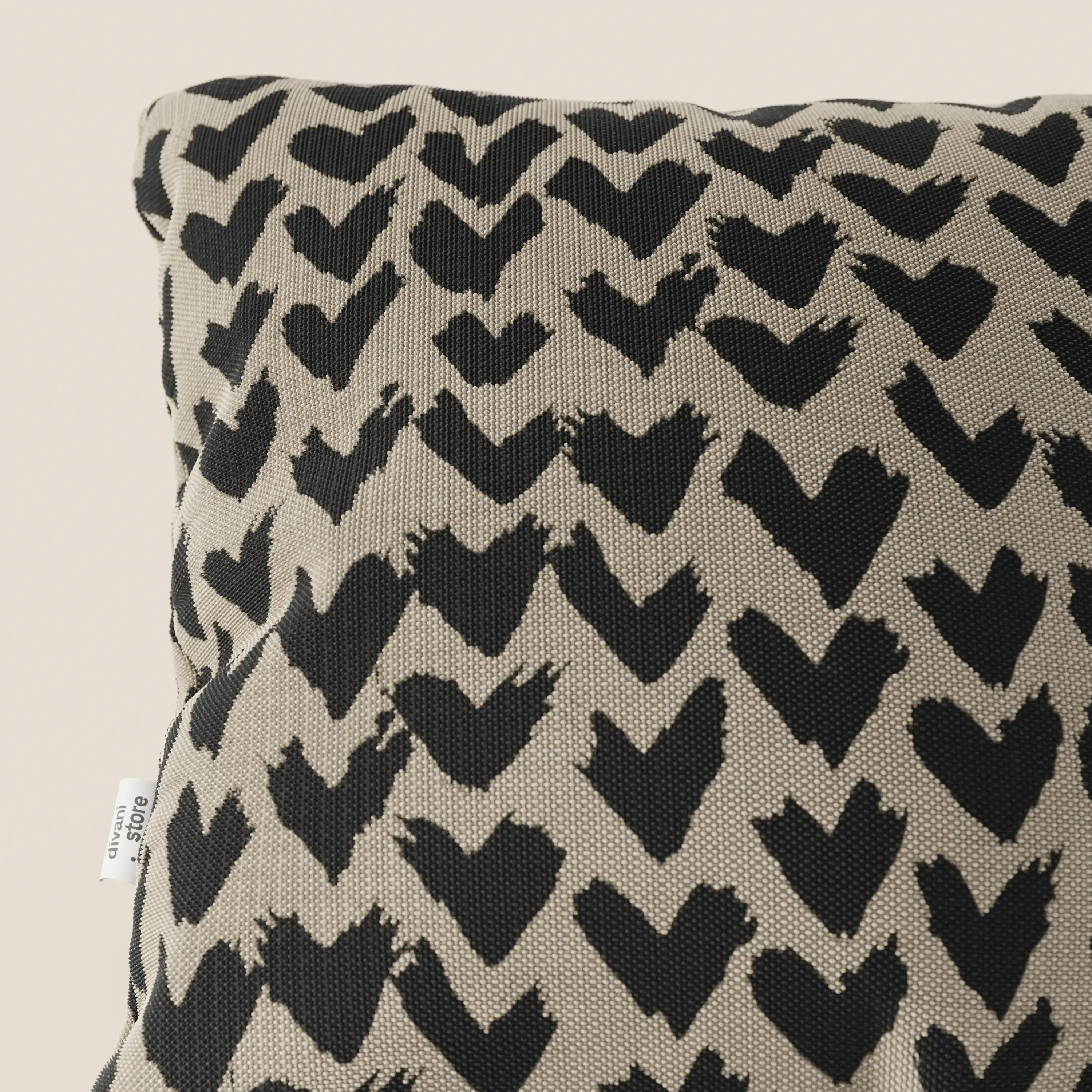 I cuscini geometrici Arrow di Divani.Store sono caratterizzati da un motivo a cuore a pennellate nere su tessuto tortora idrorepellente, con una piccola etichetta bianca sul bordo sinistro. Disponibile in vari colori.