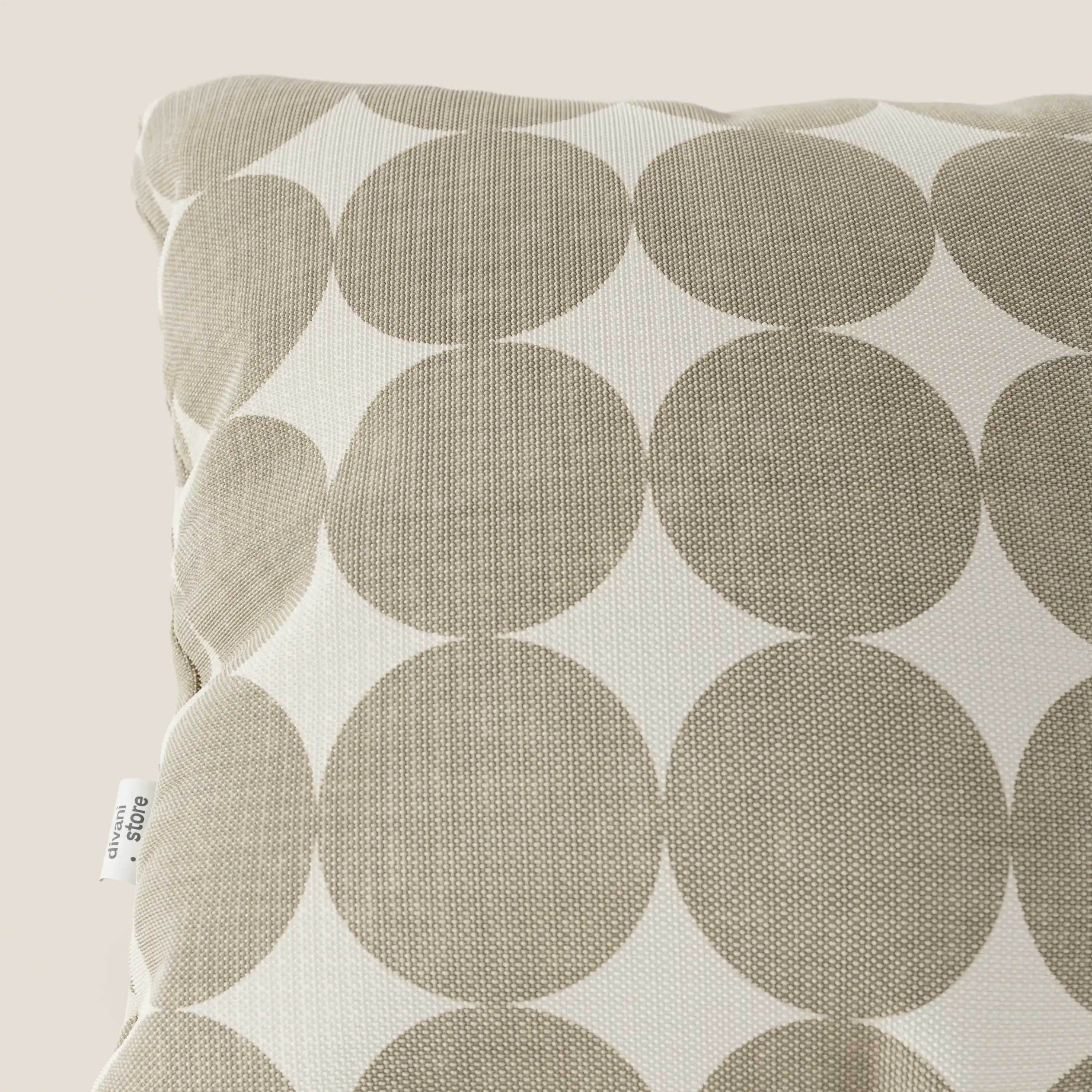 Primo piano dei cuscini geometrici Dot di Divani.Store in tessuto idrorepellente beige, con disegno a cerchi sovrapposti. La trama è visibile e sulla cucitura sinistra è applicata una piccola etichetta bianca con testo nero.