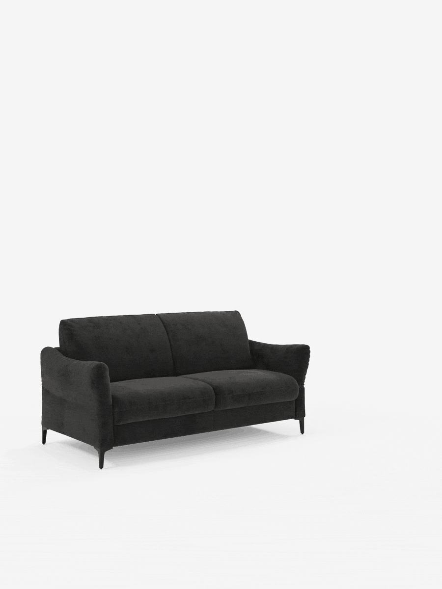 Su uno sfondo bianco semplice spicca il divano letto Dalia di Divani.Store: un moderno divano a due posti nero con morbidi cuscini, braccioli sottili e quattro gambe corte. Questa ambientazione minimalista mette in risalto l’elegante divano, rivestito in tessuto Vellutino T30, un tessuto contemporaneo e resistente alle macchie. Grazie al suo materasso H18 (18 cm) di alta qualità, questo versatile complemento d’arredo si trasforma facilmente in un comodo letto, offrendo eleganza e praticità per qualsiasi