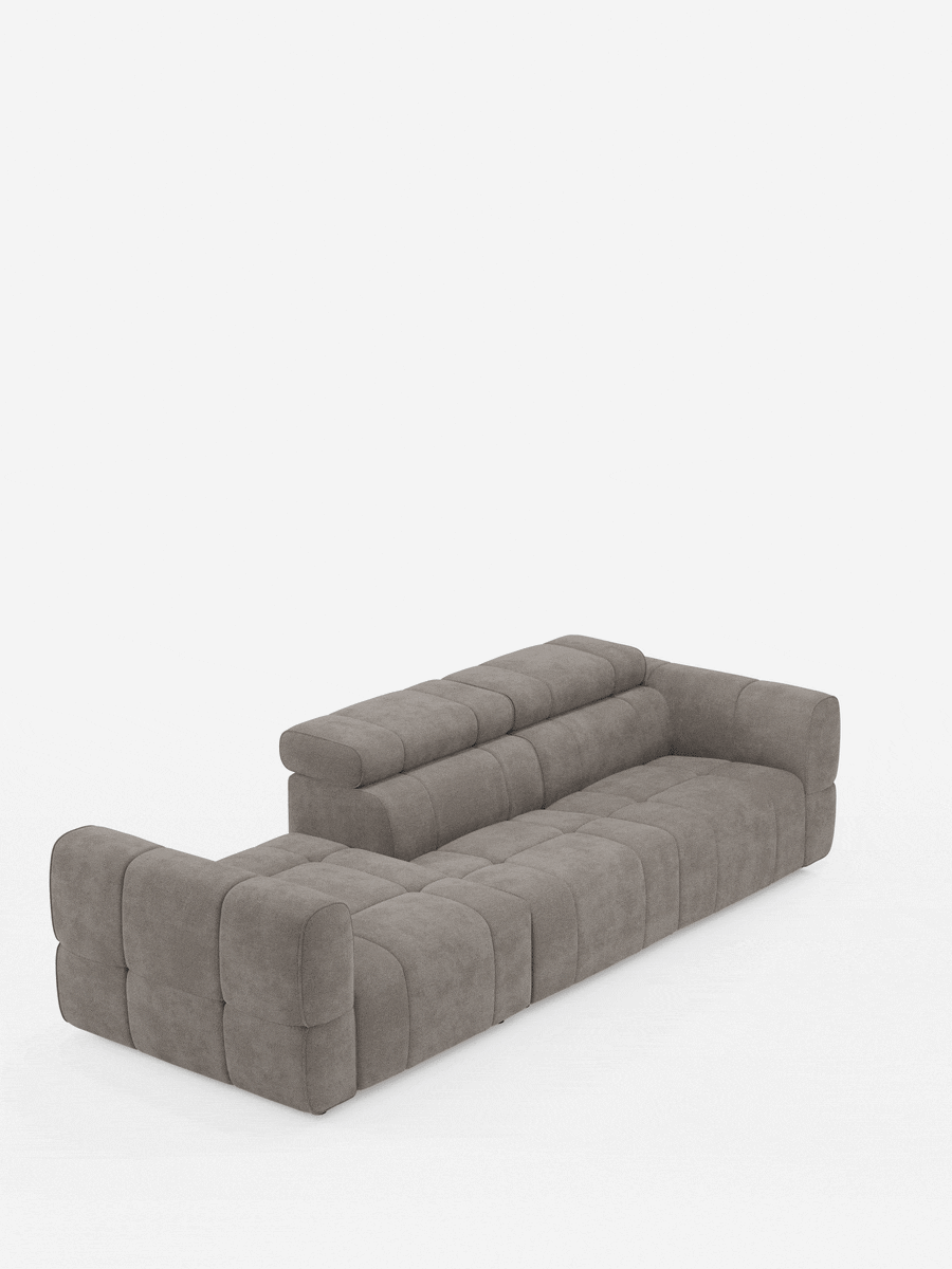 Un divano componibile Giotto color taupe con estremità aperta – opzione relax elettrico in tessuto smacchiabile T23 – è posizionato su uno sfondo bianco, caratterizzato da un motivo a griglia trapuntato e da un’estremità aperta sul lato sinistro.