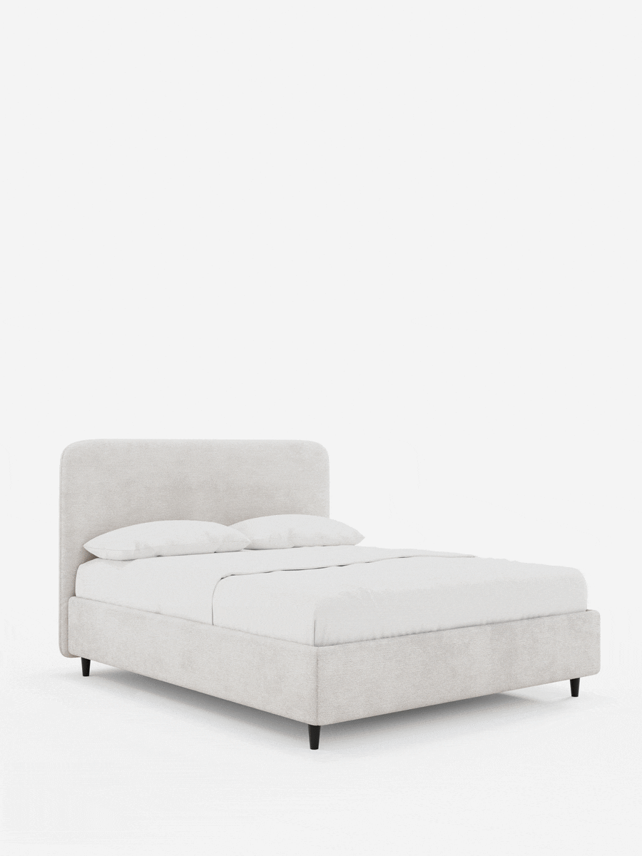 Il letto KAELOS minimal imbottito – con contenitore, gambe alte e testiera arrotondata in tessuto ciniglia – presenta una testiera alta e arrotondata di colore beige, gambe sottili nere e biancheria da letto bianca su uno sfondo bianco sporco.