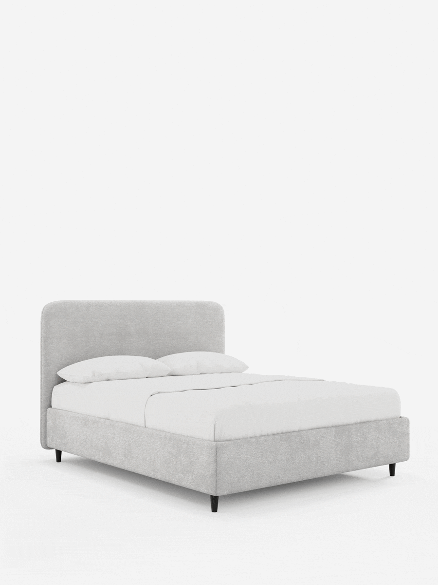 KAELOS, letto imbottito in stile minimalista, con testiera arrotondata in ciniglia grigio chiaro, biancheria da letto bianca e sottili gambe affusolate nere su sfondo bianco.