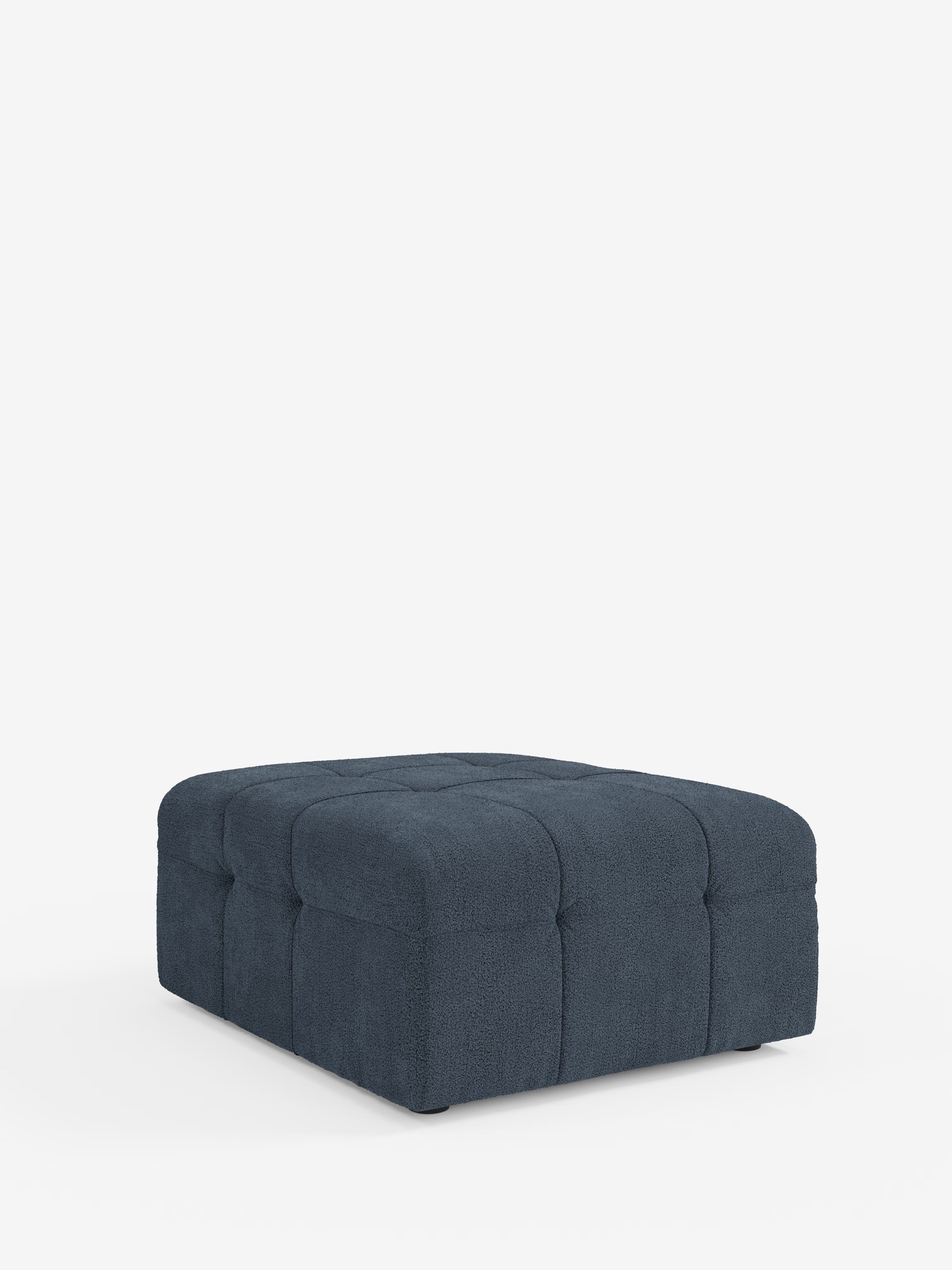 Un pouf quadrato in bouclé blu scuro con dettagli capitonné sui lati e sulla parte superiore, discretamente sostenuto da piccoli piedini su uno sfondo bianco a tinta unita: il pouf e modulo Mosaic in bouclé di Divani.Il modello Store (96x77 cm), realizzato in tessuto T21 resistente alle macchie, dona uno stile sofisticato e un comfort versatile a qualsiasi ambiente.
