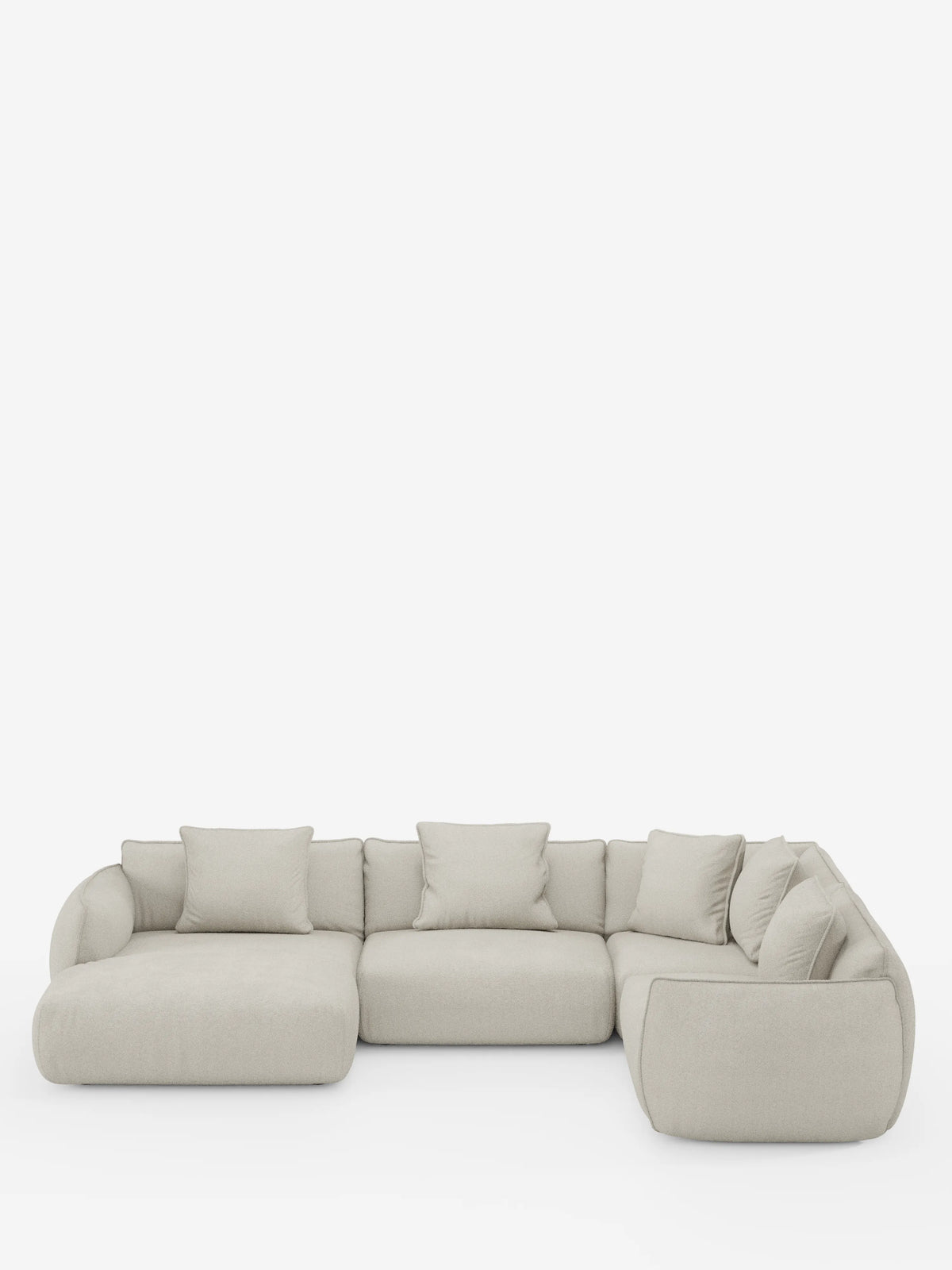 Un divano angolare panoramico componibile Nimbus in beige chiaro, con penisola e angolo in tessuto smacchiabile t33 di Divani.Store, caratterizzato da un design modulare a forma di L con morbidi cuscini e schienali bassi e arrotondati. Realizzato in Italia, comprende tre sezioni di seduta principali e sette cuscini decorativi coordinati, che risaltano su uno sfondo bianco a tinta unita.
