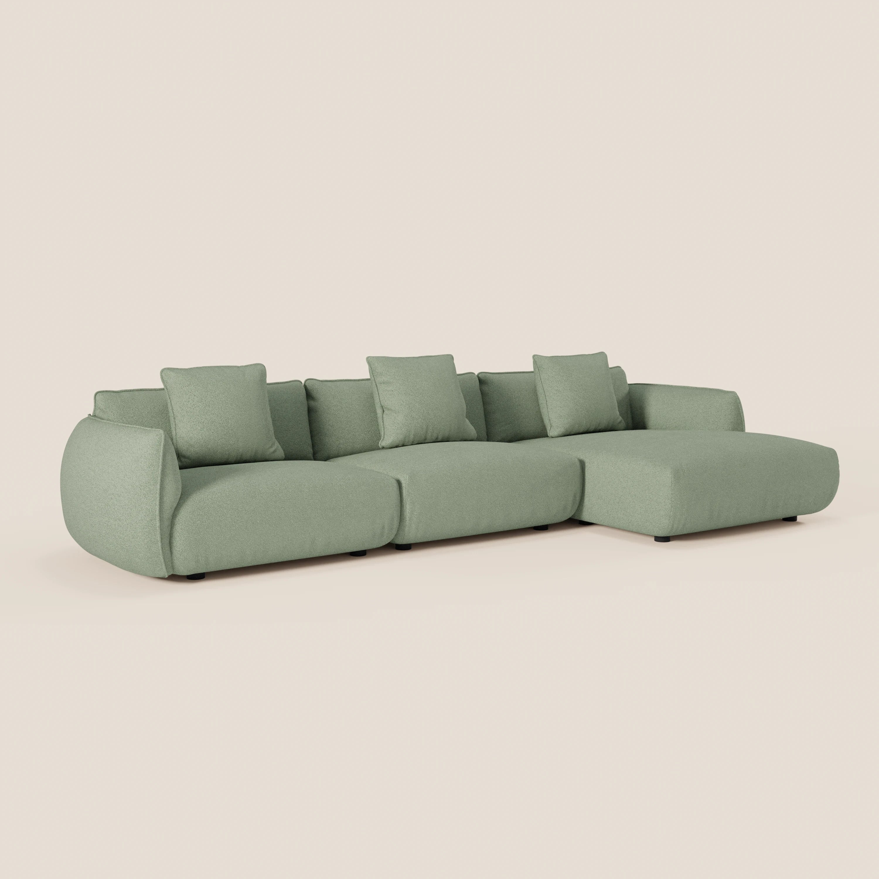 Il divano Nimbus angolare con penisola componibile di Divani.Store è caratterizzato da un tessuto effetto cotone smacchiabile verde chiaro, quattro cuscini di schienale quadrati, bordi arrotondati e una chaise destra su corti piedi scuri su sfondo chiaro.