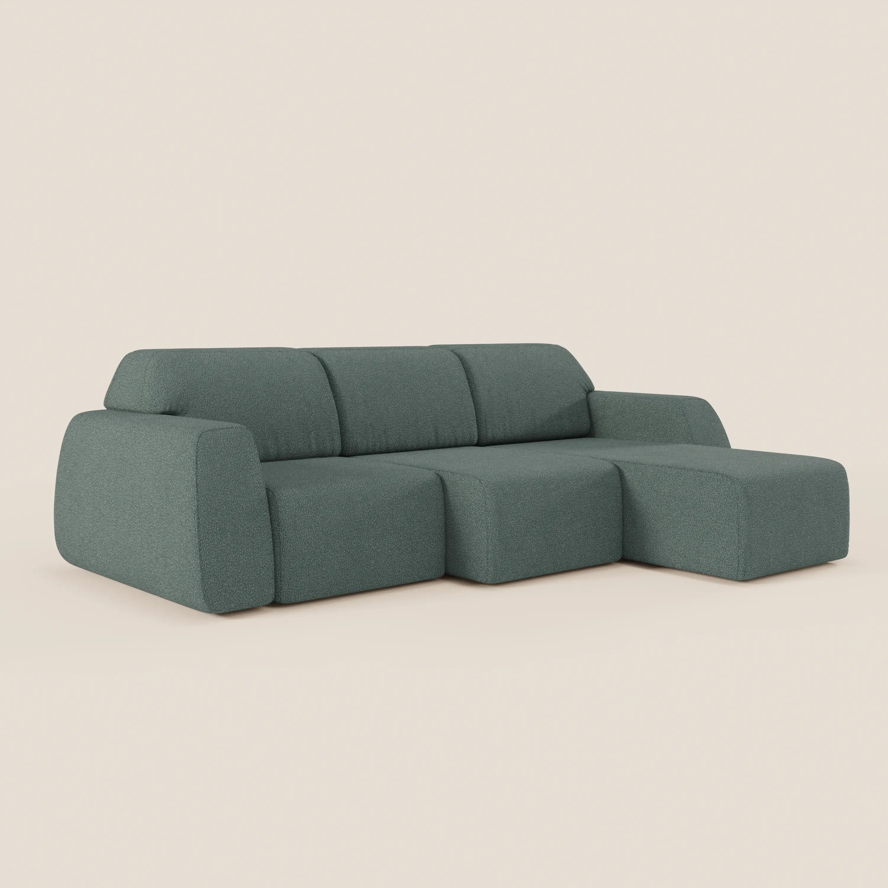 Il divano angolare Orbit con penisola reversibile e tutte le sedute allungabili in tessuto smacchiabile T33 di Divani.Store è caratterizzato da morbidi cuscini rettangolari verdi e da una versatile chaise lounge su uno sfondo bianco sporco.