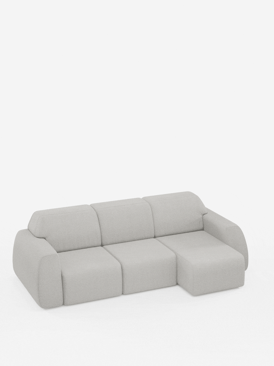 Un divano angolare Orbit contemporaneo, di colore grigio chiaro, con penisola reversibile e tutte le sedute allungabili, rivestito in tessuto smacchiabile effetto cotone T33 di Divani.Store. Il modello presenta tre posti con chaise longue sul lato destro. Questo divano modulare si caratterizza per i braccioli arrotondati e il design minimalista, qui raffigurato su uno sfondo bianco a tinta unita.