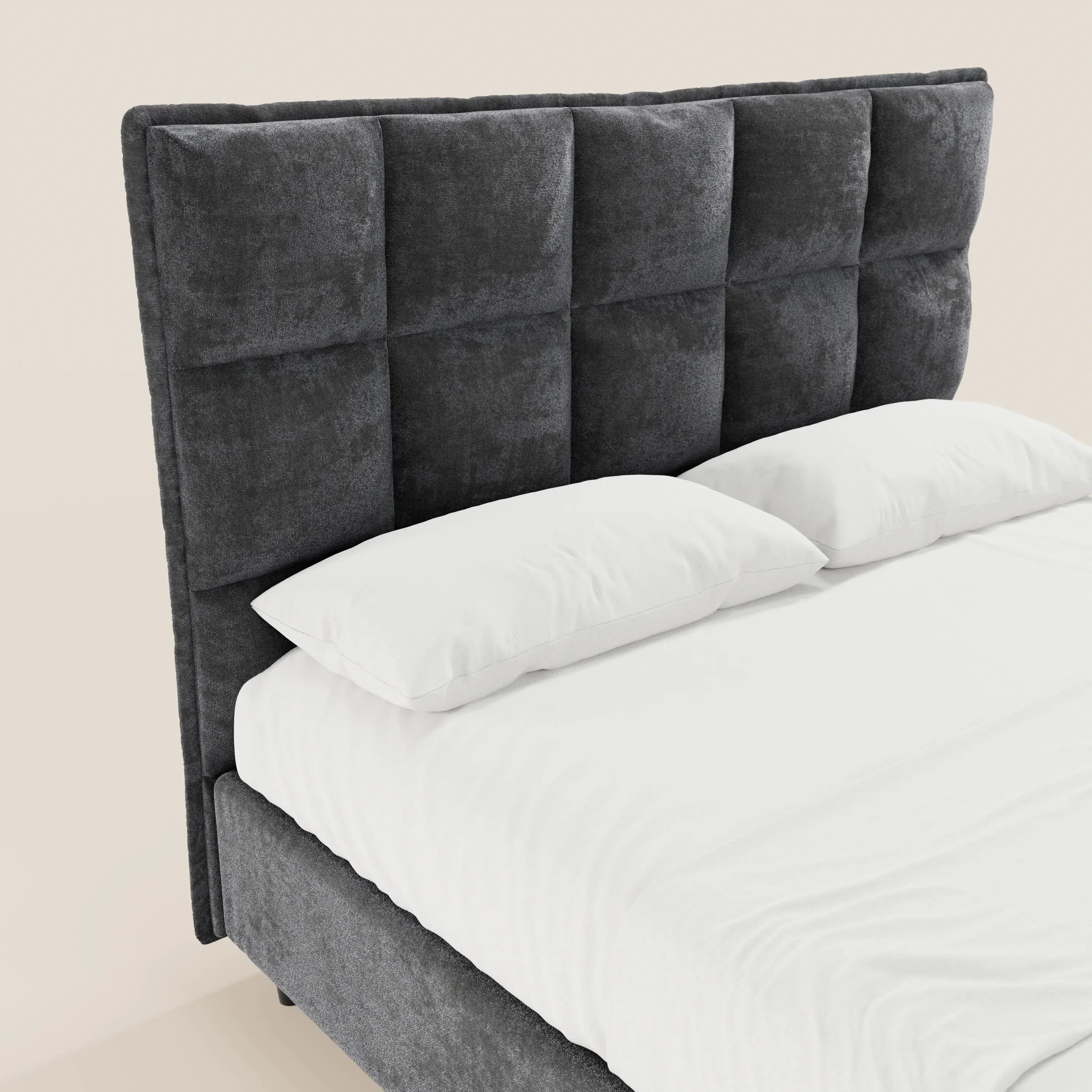 Un primo piano del letto imbottito AURO di Letti.store mette in risalto una testiera alta, di colore grigio scuro, con finitura capitonné in ciniglia certificata Oeko-Tex® e motivo a griglia quadrata; il letto è abbinato a biancheria da letto bianca, per un look minimalista e moderno.