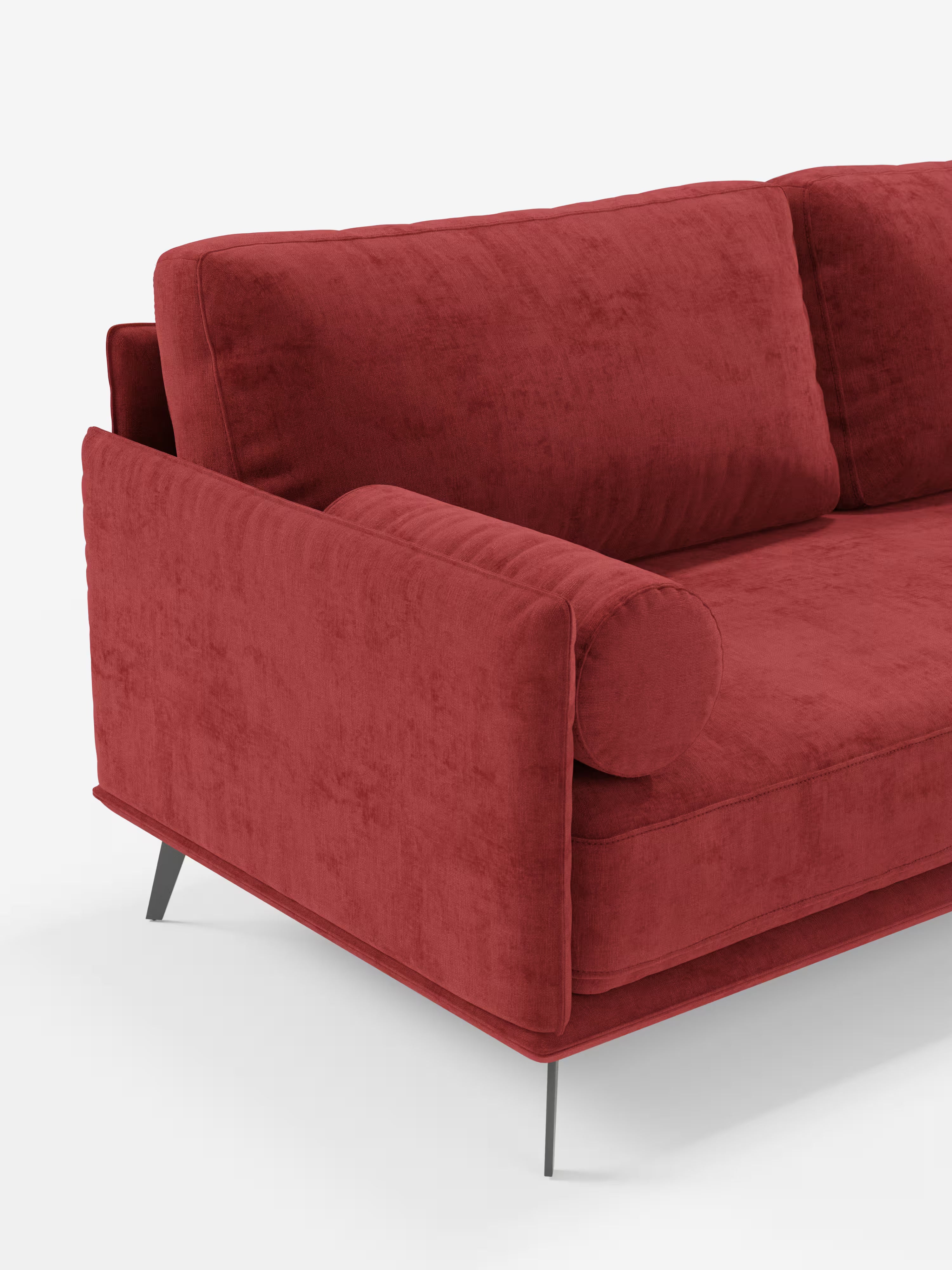 Un primo piano del divano moderno angolare con penisola "Basalto" di Divani.Store, rivestito in rosso, Made in Italy. È caratterizzato da un cuscino cilindrico, morbidi cuscini imbottiti in piuma rivestiti in tessuto T31 antimacchia, braccioli dritti e una base sottile in metallo nero. Lo sfondo è bianco a tinta unita.