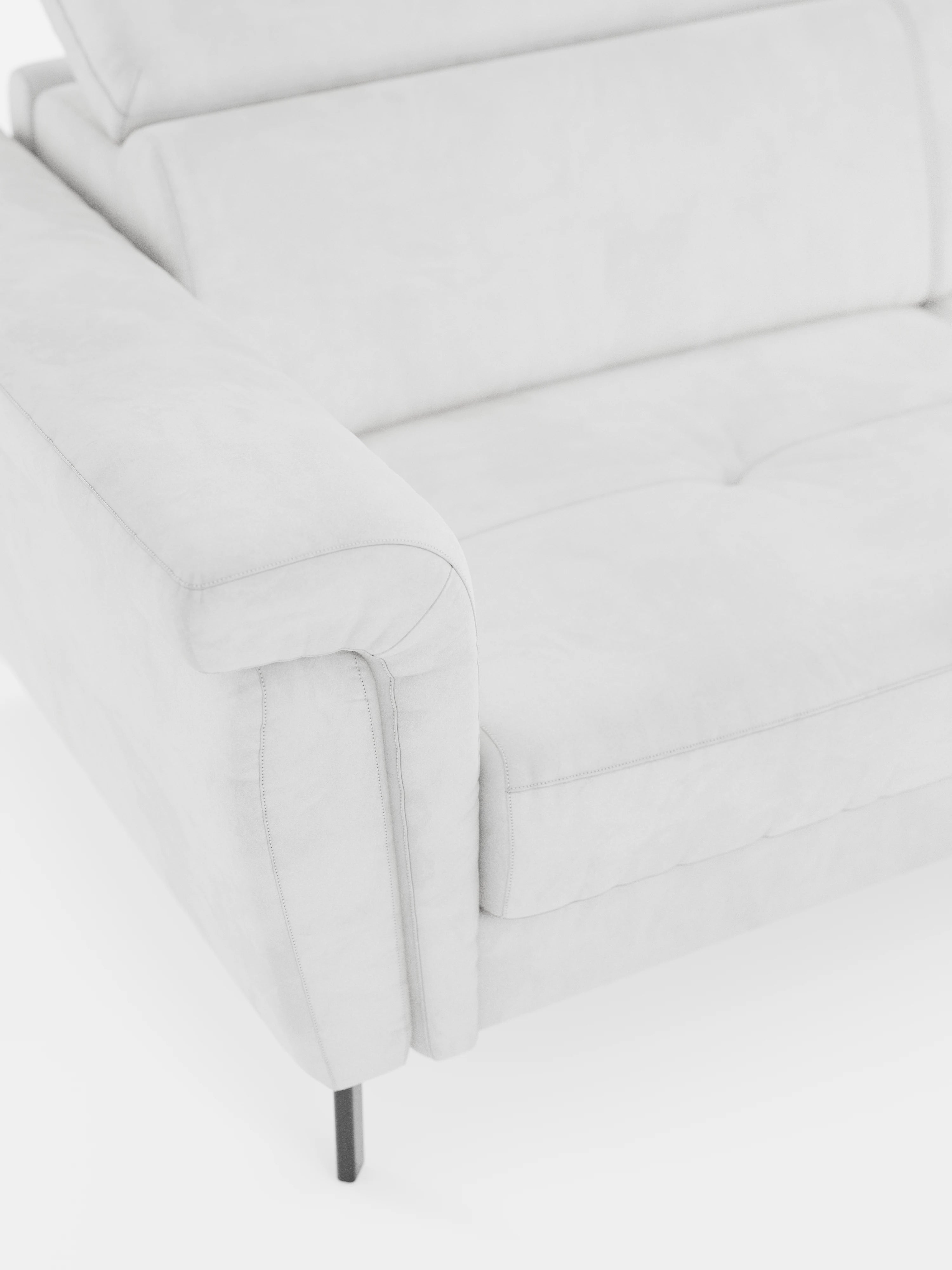 Un primo piano del divano letto di design Capri di Divani.Store, realizzato in raffinato tessuto T30 effetto velluto resistente alle macchie: si notano un bracciolo, un cuscino di seduta leggermente trapuntato e sottili gambe in metallo nero su sfondo bianco. Il rivestimento è morbido e liscio, dall’estetica minimalista, e si completa con poggiatesta regolabili per un comfort ancora maggiore.