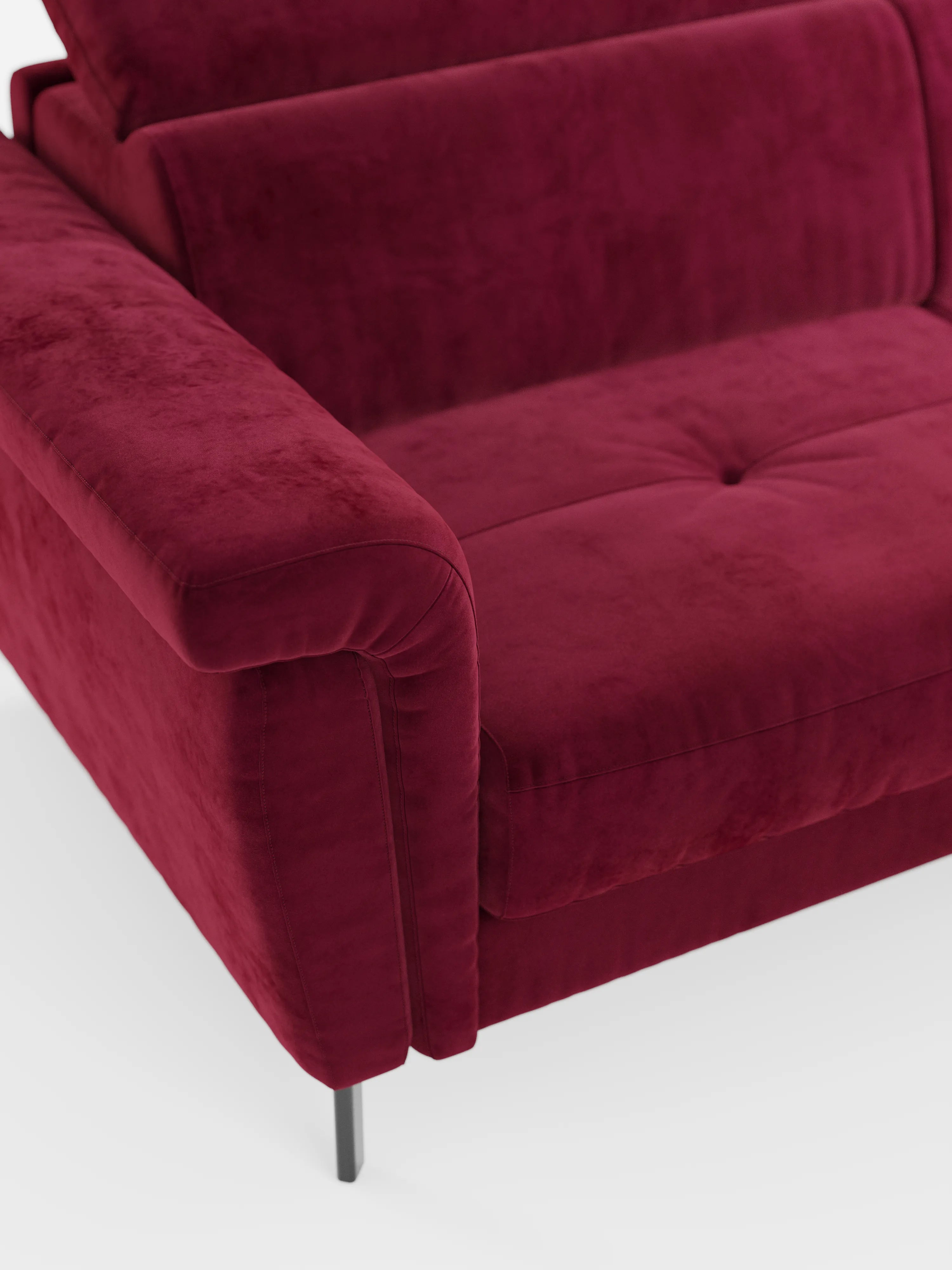 Un primo piano del divano letto di design Capri con piedini alti di Divani.Store, realizzato in raffinato tessuto effetto velluto antimacchia T30, mette in risalto il bracciolo sinistro, un cuscino di seduta con due bottoni e un'elegante gamba in metallo. Il divano presenta un aspetto morbido e materico con eleganti poggiatesta reclinabili, che risaltano su uno sfondo bianco a tinta unita.