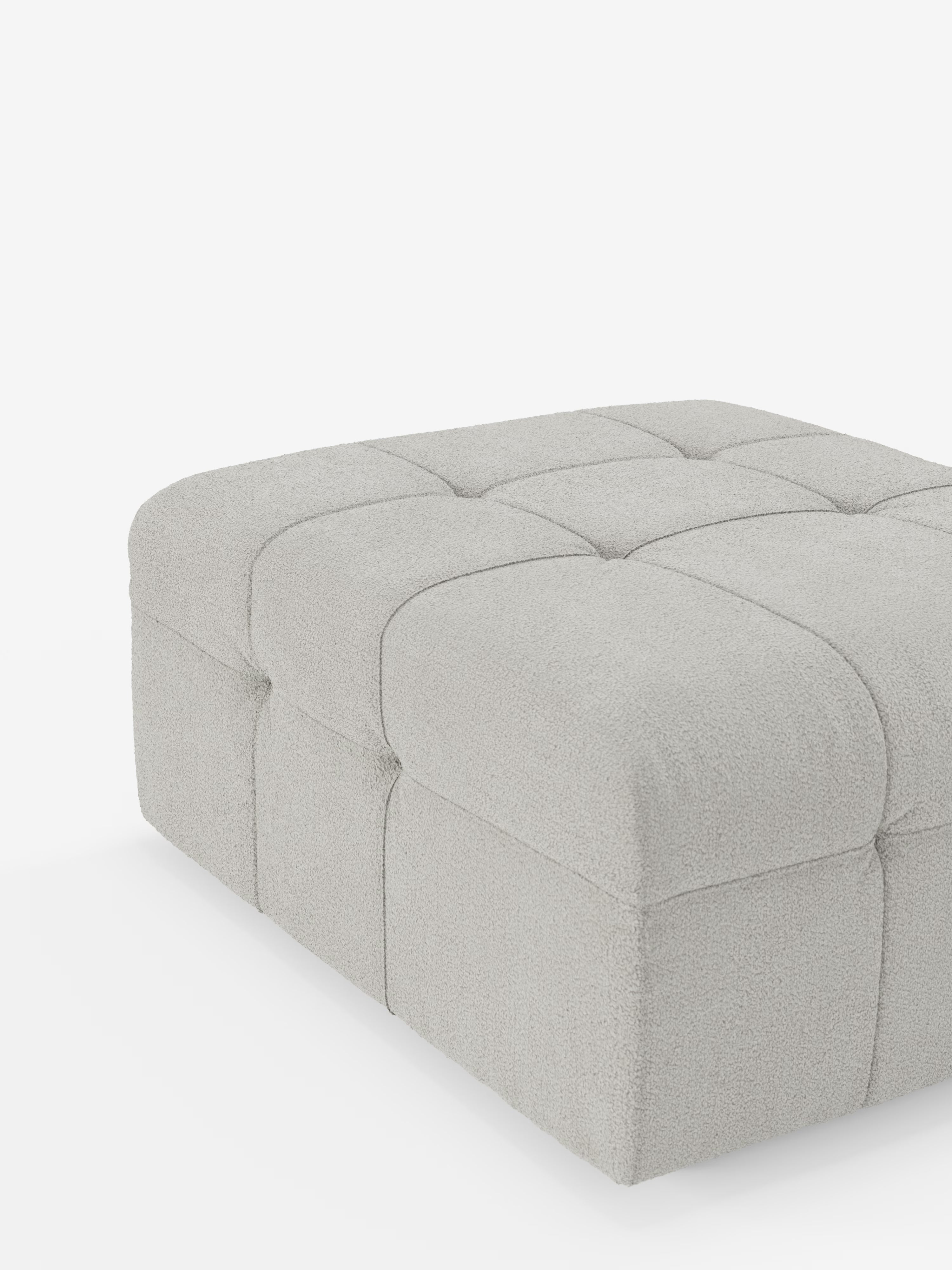 Un pouf spazioso e squadrato di Divani.Store, il modello Mosaic in bouclé (96x77 cm), è realizzato in tessuto T21 grigio chiaro, resistente alle macchie, con un morbido rivestimento trapuntato in stile capitonné. Il suo rivestimento in bouclé, morbido e dalla trama caratteristica, presenta una griglia di cuciture a vista sulla parte superiore imbottita e sui lati. Immagine raffigurata su sfondo bianco, senza gambe visibili.