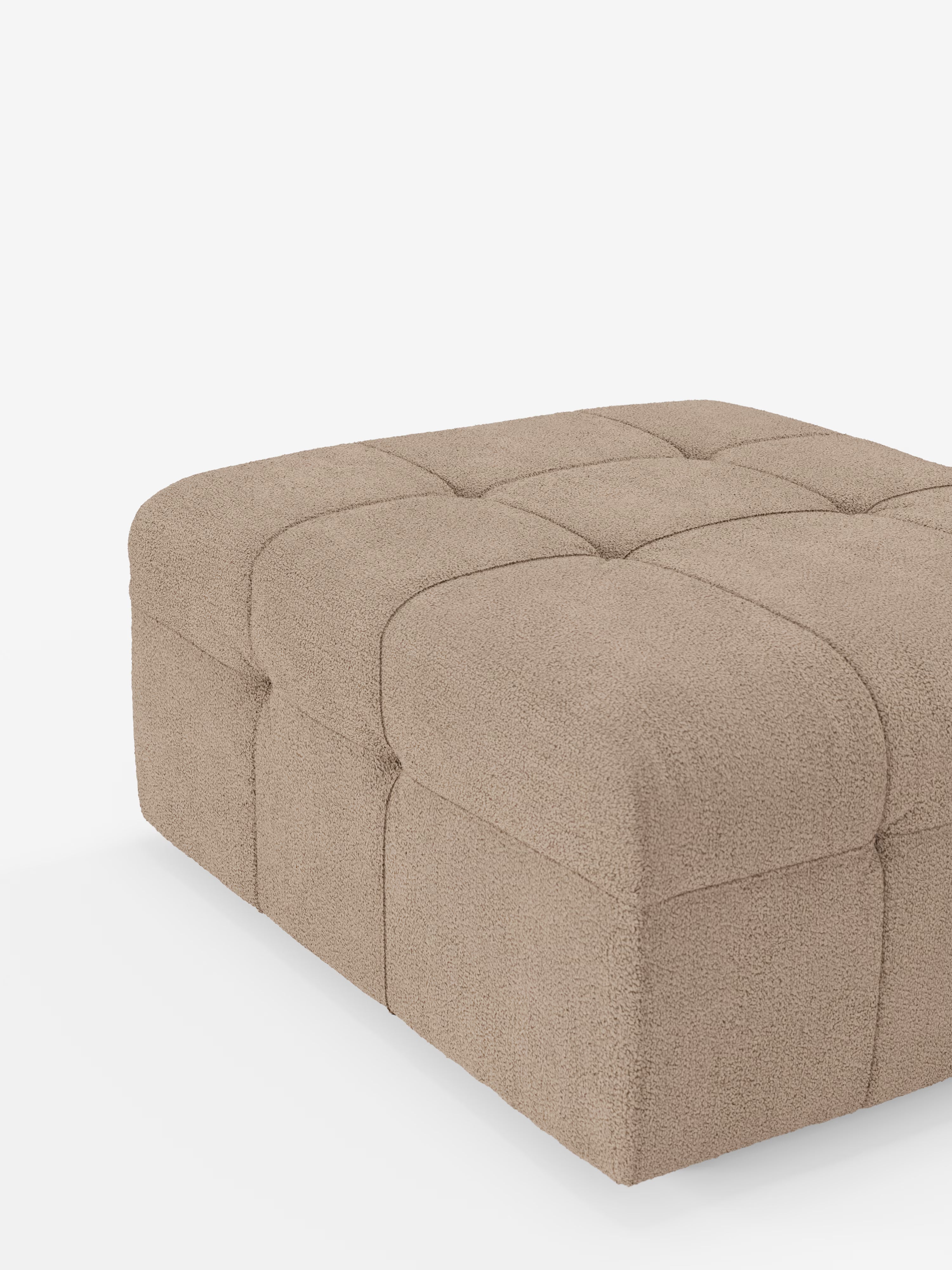 Il pouf e modulo Mosaic in bouclé di Divani.Store, dalle dimensioni di 96x77 cm, presenta un classico design capitonné con una superficie imbottita e trapuntata in tessuto T21 antimacchia. Caratterizzato da bordi arrotondati e da sottili linee cucite che dividono la superficie in quadrati, il morbido rivestimento testurizzato di questo pouf beige risalta magnificamente sullo sfondo bianco.