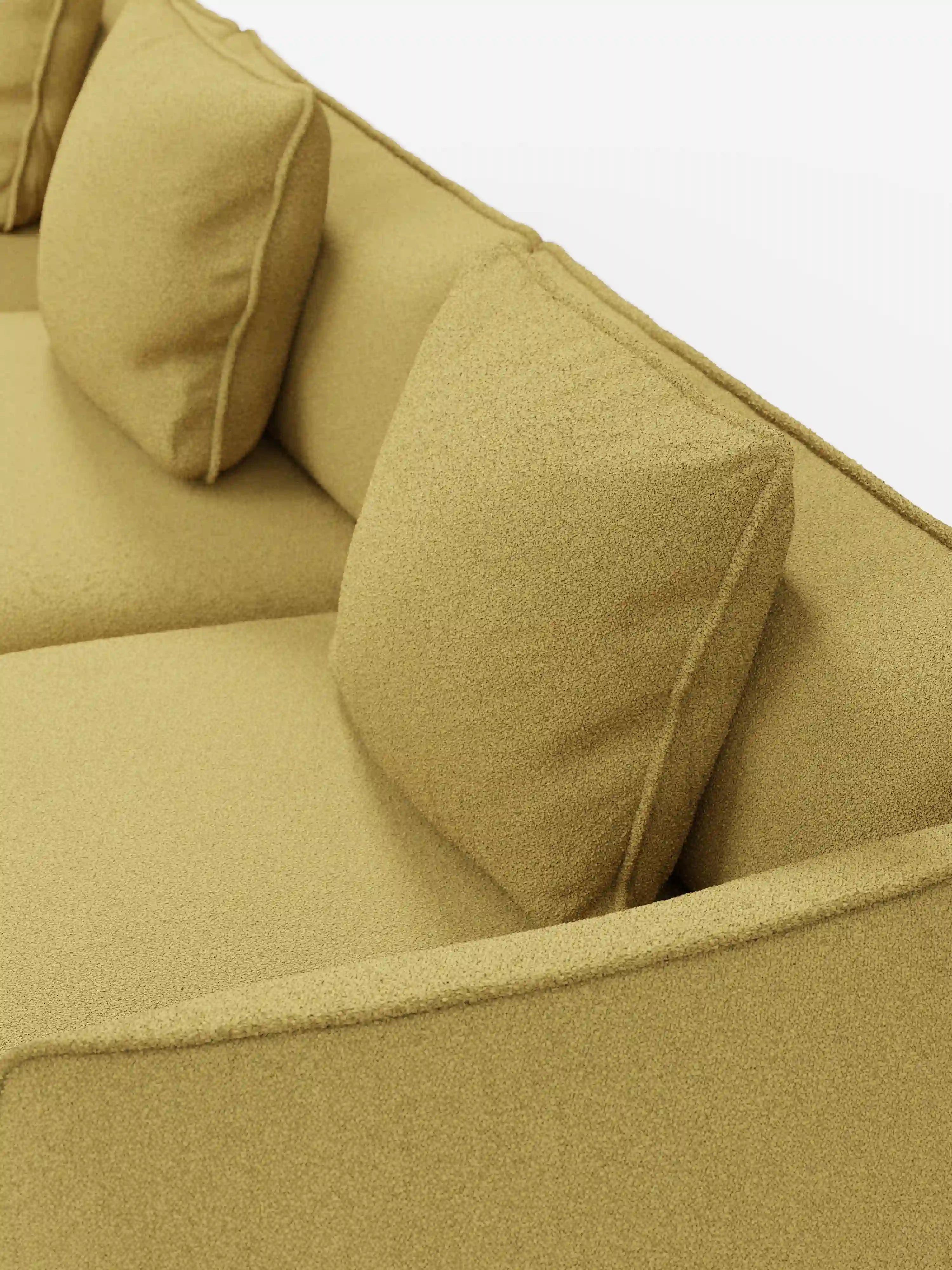 Un primo piano del divano modulare a 3 posti Nimbus, realizzabile in morbido tessuto smacchiabile effetto cotone T33 di Divani.Store, mette in risalto il suo moderno rivestimento giallo senape, i due cuscini quadrati coordinati e il design elegante e minimalista. L’immagine mette in risalto la morbidezza del tessuto effetto cotone antimacchia e le linee pulite di questo divano componibile.