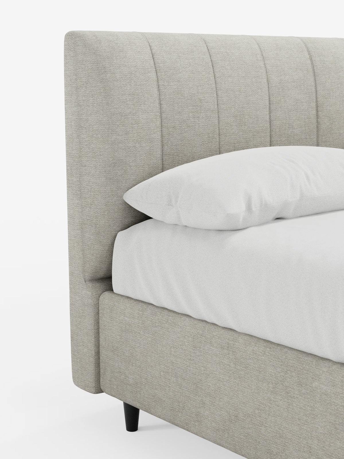 Un primo piano del letto imbottito ONYX con contenitore e testiera verticale in tessuto certificato Oeko-Tex® di Letti.store, caratterizzato da una struttura imbottita color beige chiaro e da una testiera con canalature verticali. Il letto è abbinato a biancheria da letto bianca e a un cuscino bianco, con gambe corte e scure che risaltano sullo sfondo bianco a tinta unita.