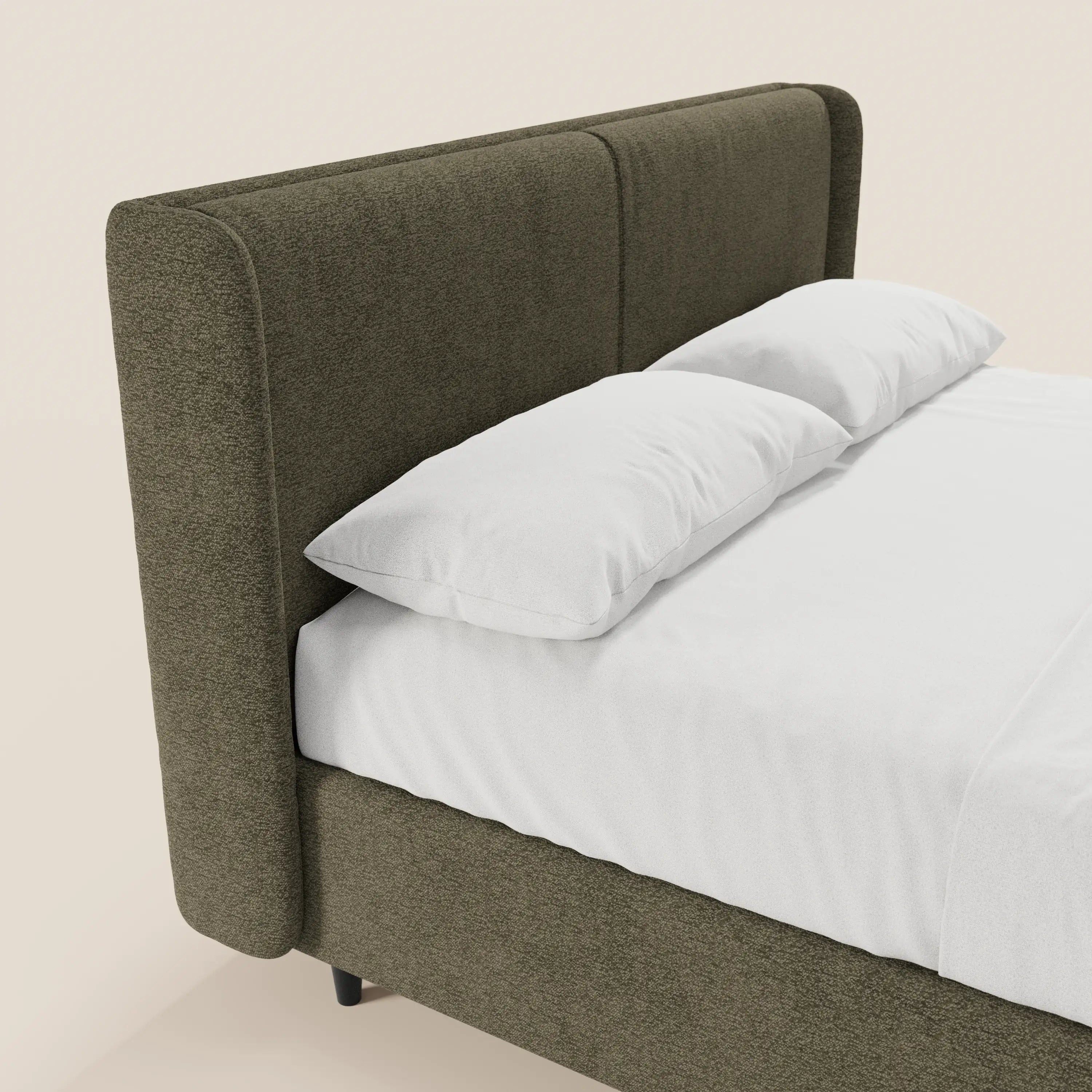 Il modello VALKIRIA di Letti.store è un letto dal design moderno rivestito in tessuto verde oliva certificato Oeko-Tex®, caratterizzato da una testiera avvolgente con 2 cuscini imbottiti e vano portaoggetti. Nella foto, ripreso di profilo, è abbinato a lenzuola bianche, due cuscini e uno sfondo chiaro a tinta unita.