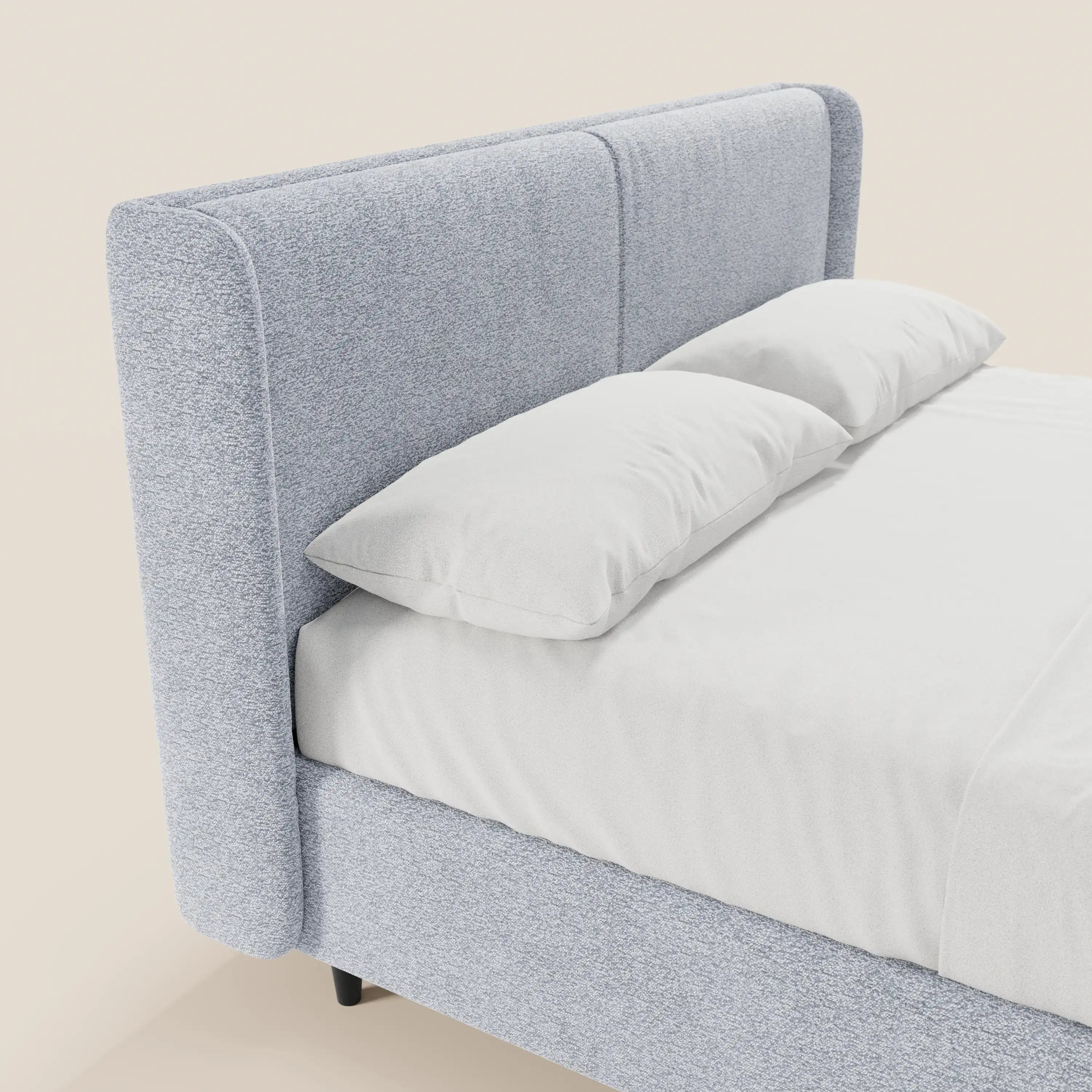 Il letto di design VALKIRIA di Letti.store presenta una struttura rivestita in grigio chiaro certificata Oeko-Tex®, una testiera avvolgente e 2 cuscini imbottiti. Del letto moderno è visibile solo una parte, con lenzuola bianche su uno sfondo chiaro e semplice.