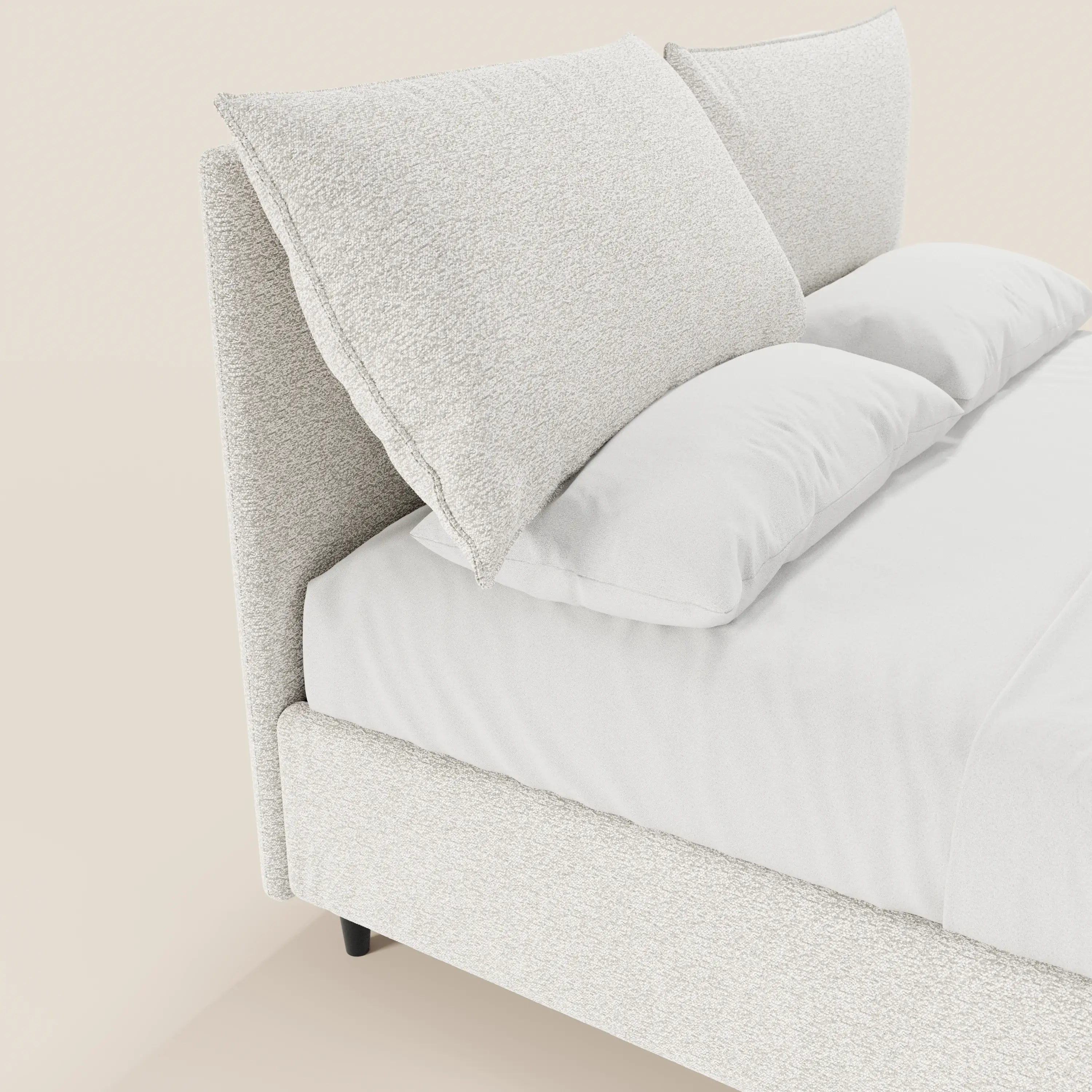 Un primo piano del letto imbottito ZAYRON con contenitore di Letti.store, in tessuto Oeko-Tex®, mostra morbidi cuscini regolabili e lenzuola bianche; la struttura moderna si staglia su uno sfondo beige.