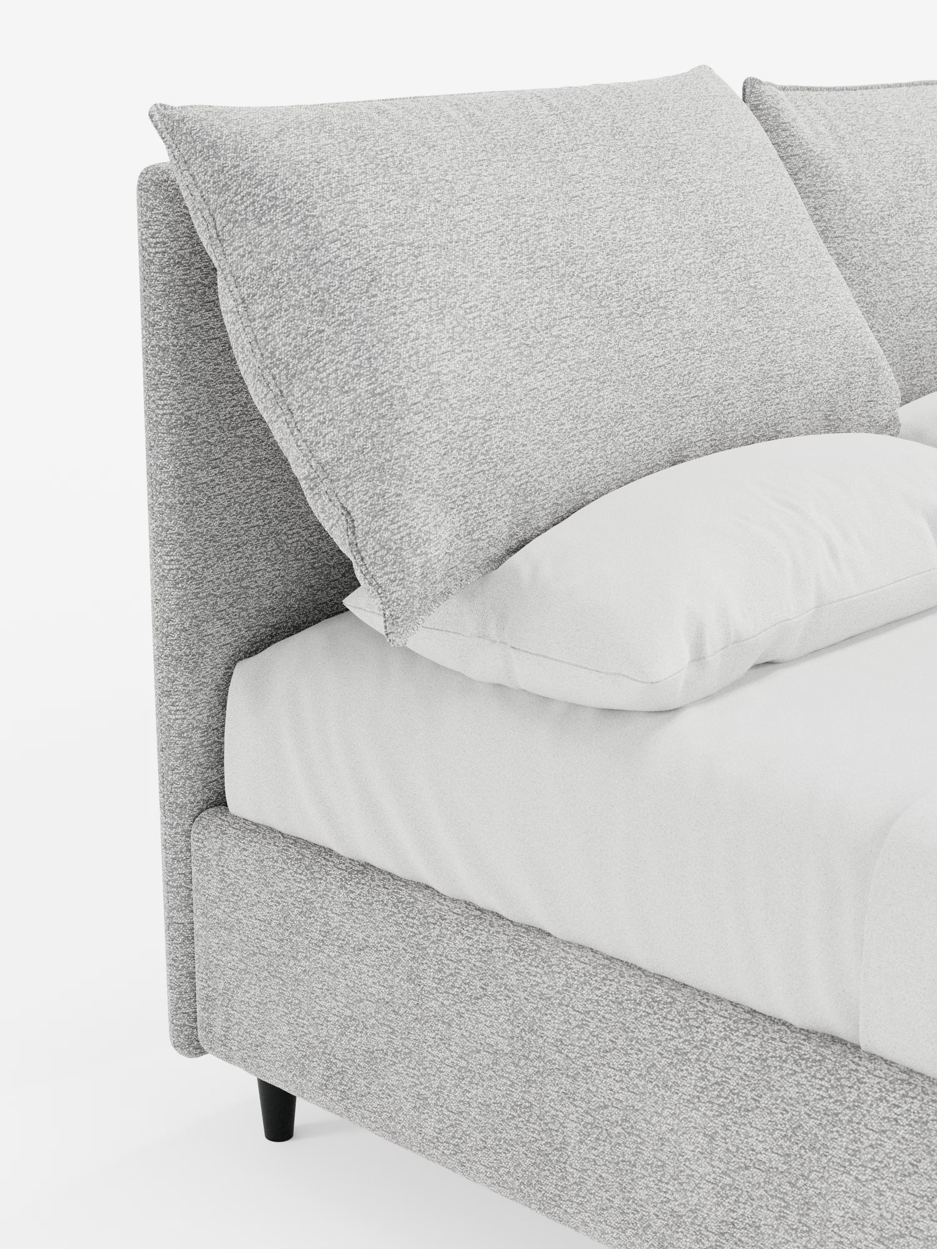 Primo piano del letto imbottito ZAYRON con contenitore e morbidi cuscini regolabili di Letti.store, caratterizzato da un design moderno con testiera e struttura imbottite in grigio chiaro, certificate Oeko-Tex®. Il letto è abbellito da un grande cuscino grigio angolare, un cuscino bianco e biancheria da letto candida. Poggia su brevi gambe nere su uno sfondo bianco a tinta unita, che ne esalta le texture morbide e le linee pulite.