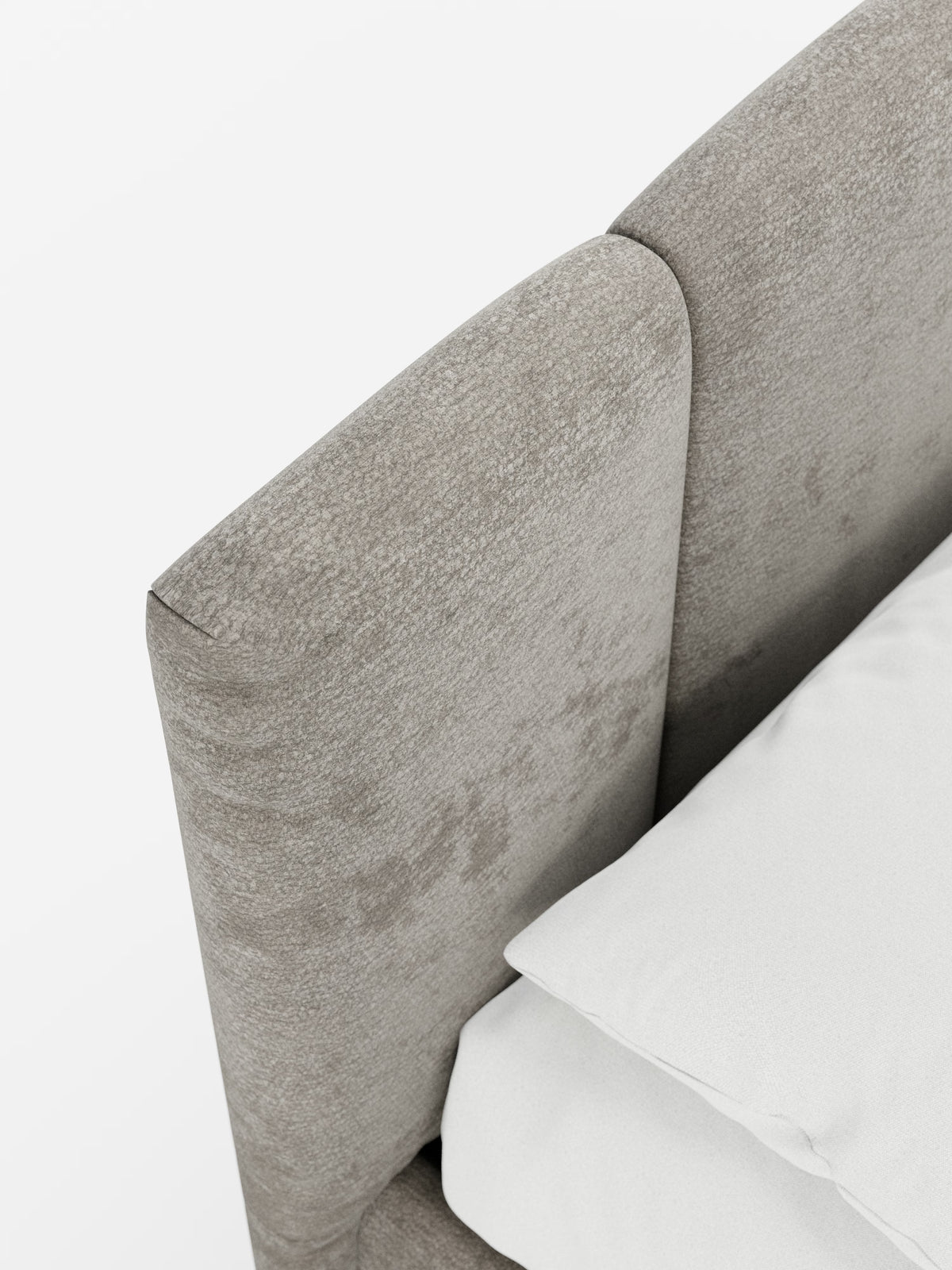 Primo piano del letto imbottito ARKAM con contenitore e testiera a lavorazione verticale di Letti.store, caratterizzato da una testiera imbottita in grigio chiaro con texture e dal design moderno e arrotondato, realizzata in tessuto certificato Oeko-Tex®. Nell’angolo in basso a destra, su uno sfondo bianco a tinta unita, sono visibili parte di un cuscino bianco e di un lenzuolo.