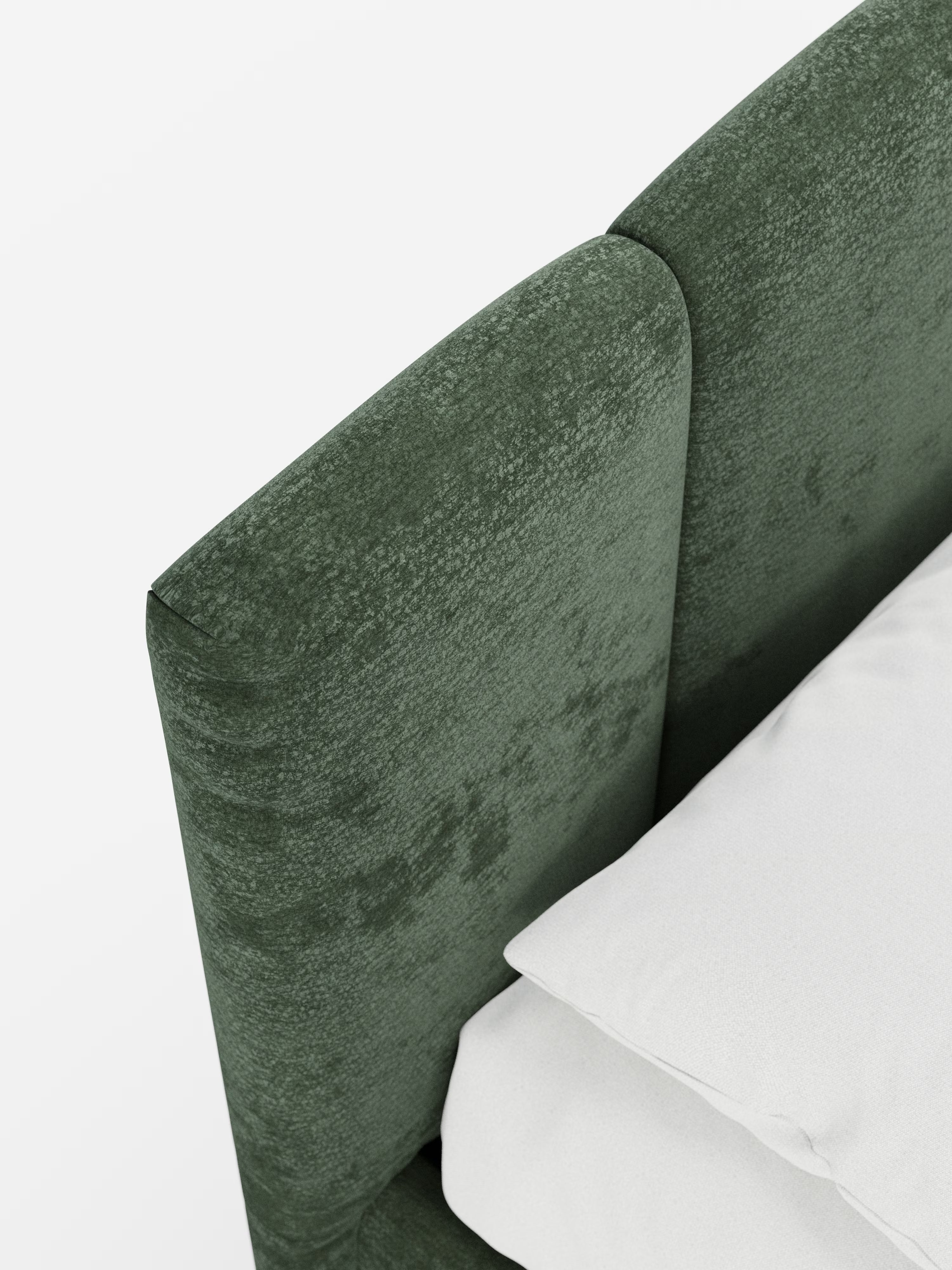 Primo piano del letto imbottito ARKAM di Letti.store, caratterizzato da una testiera verde con cuciture verticali, rivestita in tessuto certificato Oeko-Tex®, ripresa dall’alto. Un cuscino bianco e una parte di un lenzuolo bianco poggiano sul materasso accanto all’elegante testiera in stile shabby chic. Lo sfondo è bianco e uniforme.