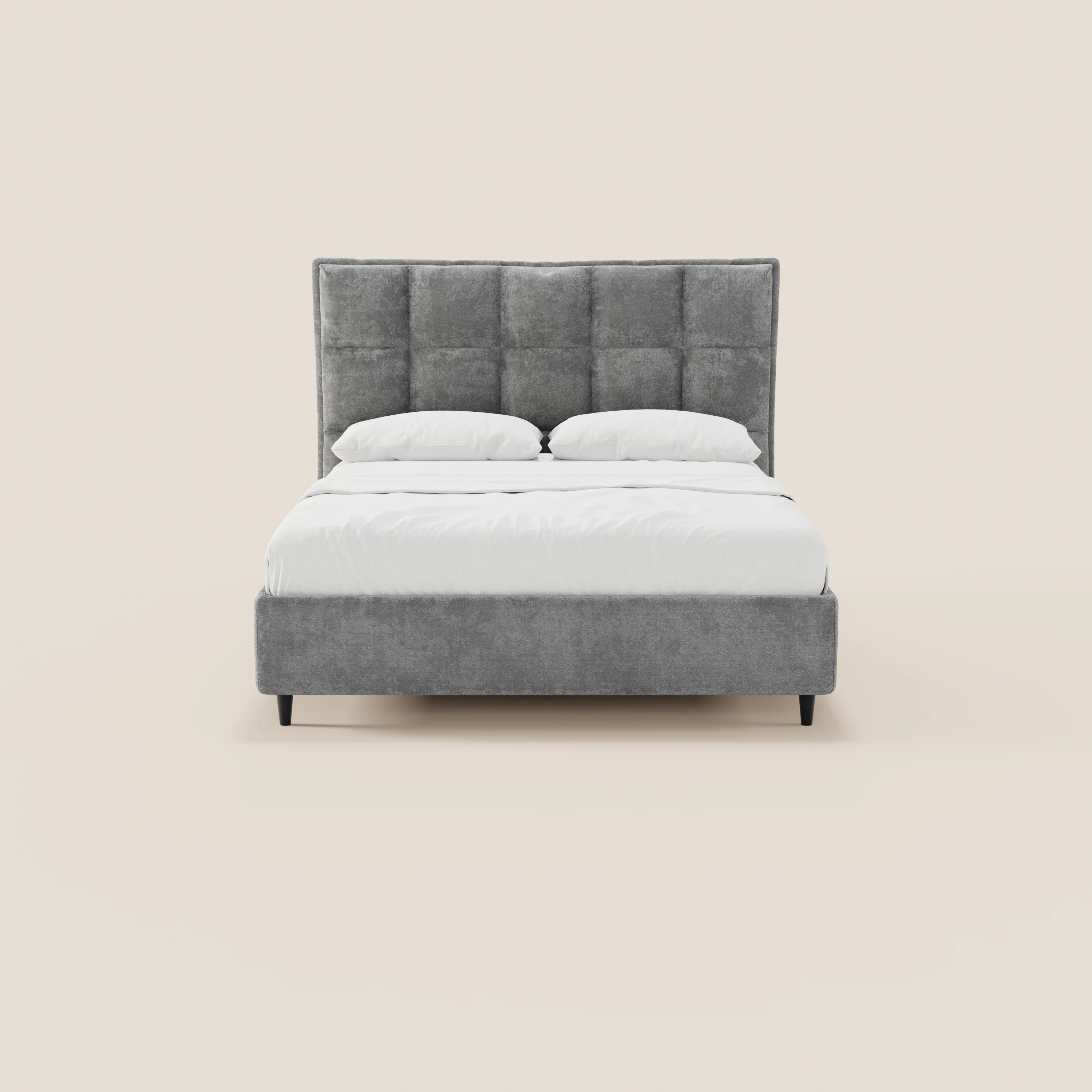 Il letto imbottito AURO di Letti.store presenta una testiera alta, capitonné a quadri, in ciniglia grigia certificata Oeko-Tex®, con struttura in tinta, gambe nere e vano contenitore. Nella foto è raffigurato con la biancheria da letto bianca ben rifatta su uno sfondo beige chiaro a tinta unita.