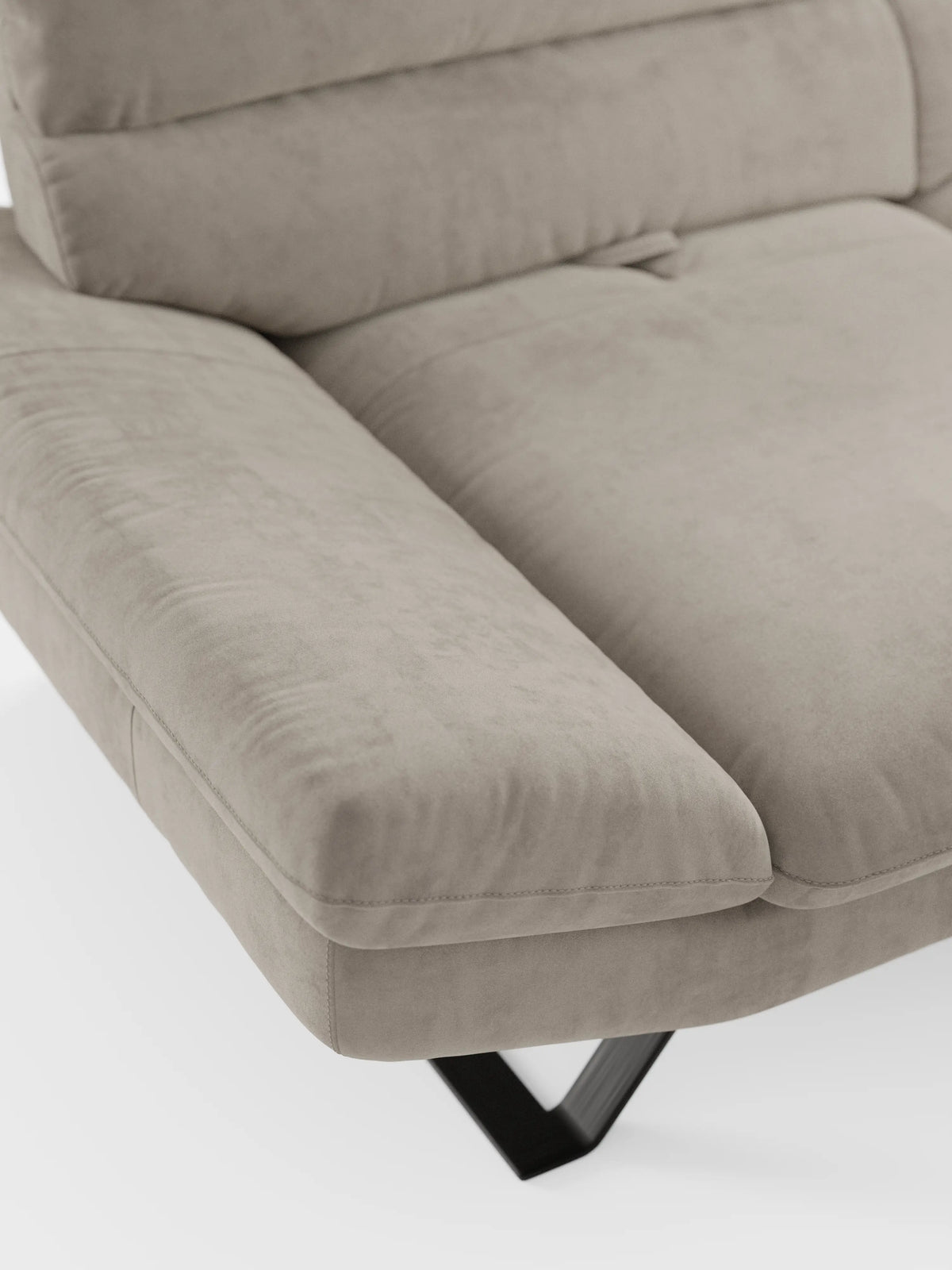 Primo piano del divano Eclipse dal design moderno di Divani.Store, qui presentato come un raffinato divano angolare rivestito in elegante microfibra T11 smacchiabile, simile alla pelle scamosciata, color taupe. L'imbottitura morbida e gli ampi braccioli ne sottolineano lo stile contemporaneo, mentre le cuciture a vista e gli schienali traslanti offrono un comfort personalizzabile. I caratteristici piedini alti in metallo a forma di V di colore nero completano il look moderno sullo sfondo bianco.
