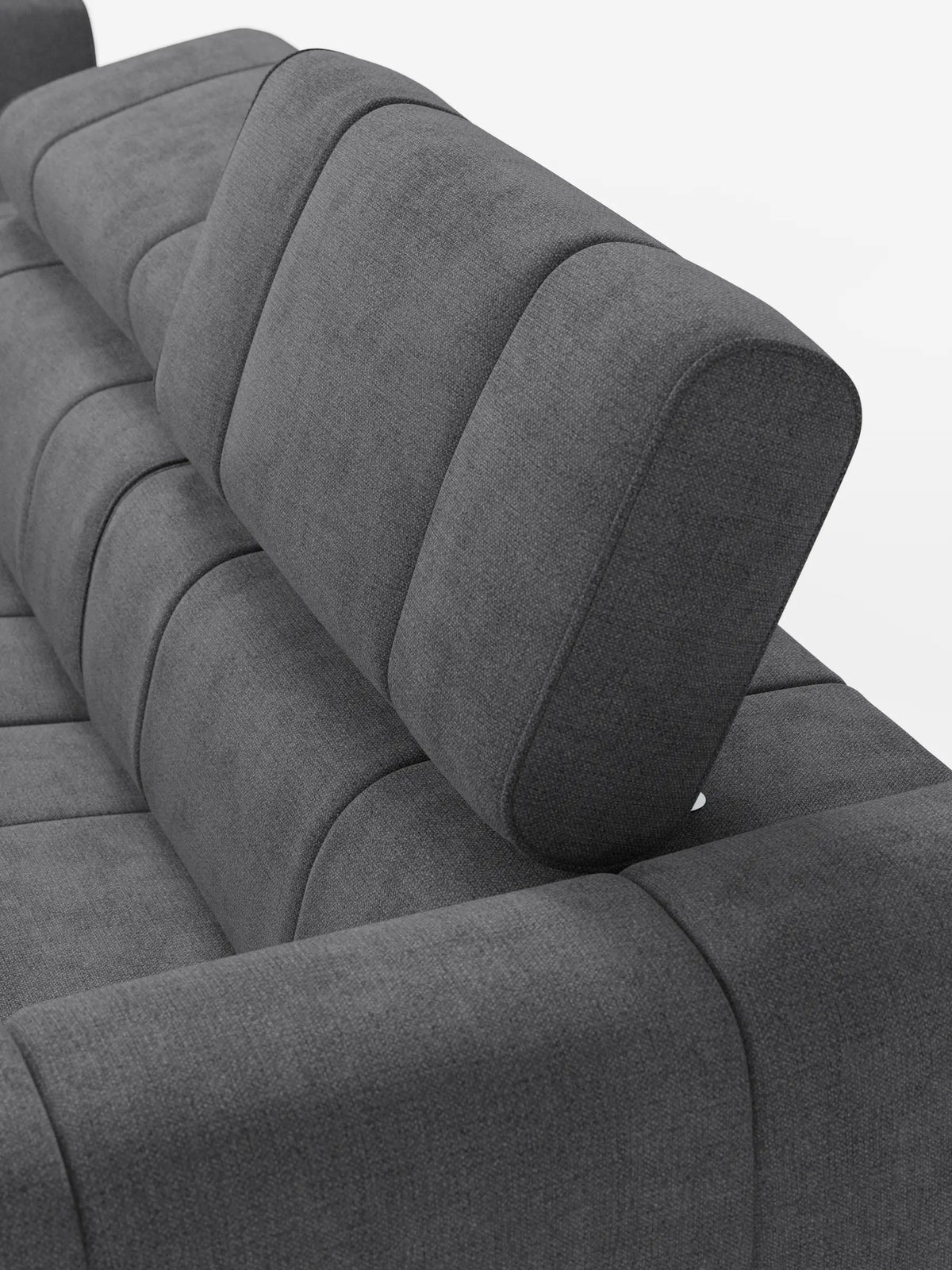 Un primo piano del divano componibile Giotto, color grigio scuro, con terminale aperto – opzione relax elettrico in tessuto smacchiabile T23, caratterizzato da trapuntatura a canalini verticali, poggiatesta regolabili e finitura in tessuto testurizzato su sfondo bianco.
