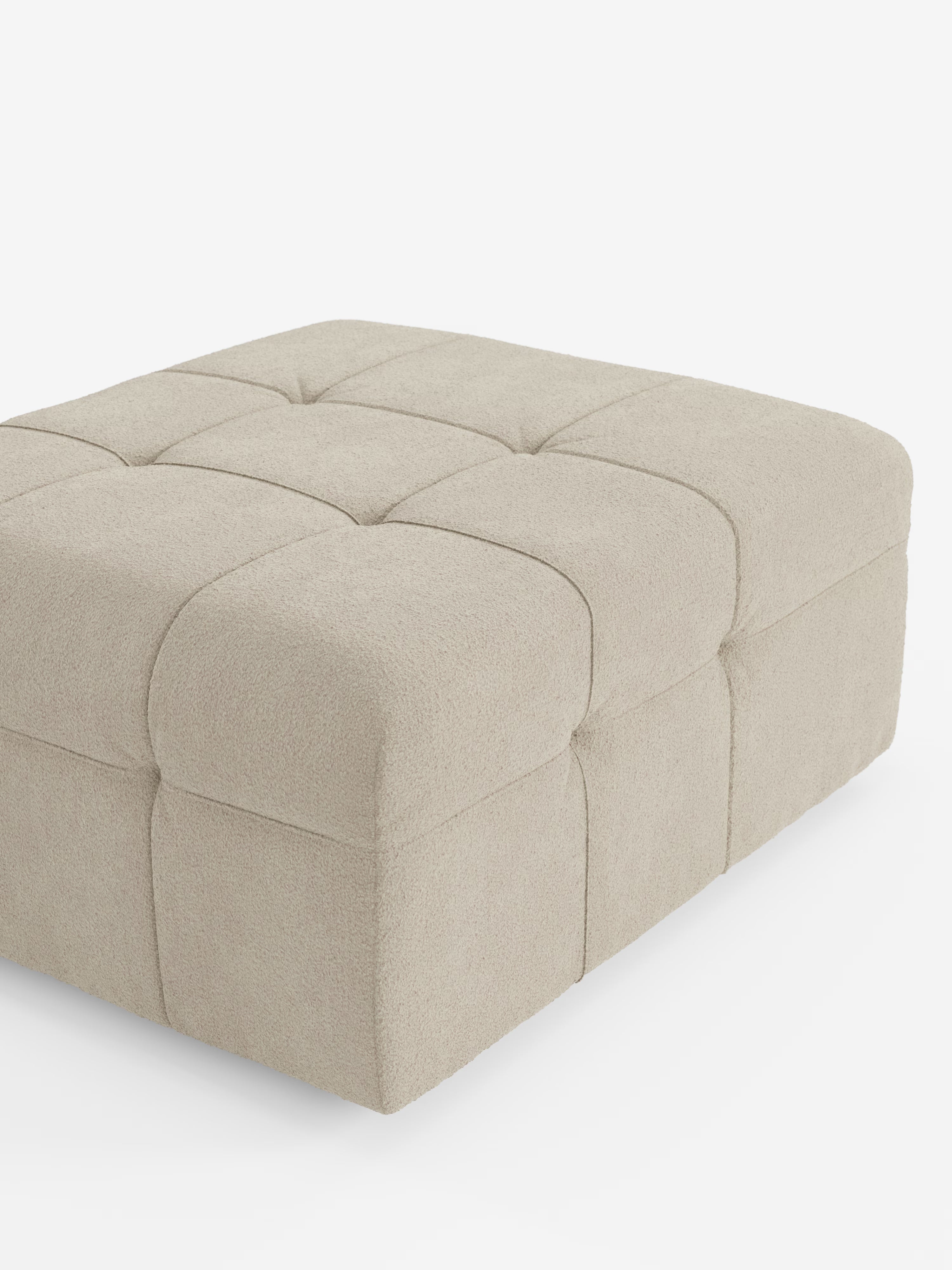 Un pouf e modulo Mosaic color beige in bouclé di Divani.Store, caratterizzato da un design quadrato capitonné a capitoni suddiviso in nove sezioni con cuciture a vista. Con dimensioni di 96x77 cm, questo pouf di produzione italiana è realizzato in tessuto smacchiabile T21 resistente alle macchie e presenta bordi delicatamente arrotondati. Sono visibili solo due lati su uno sfondo bianco.