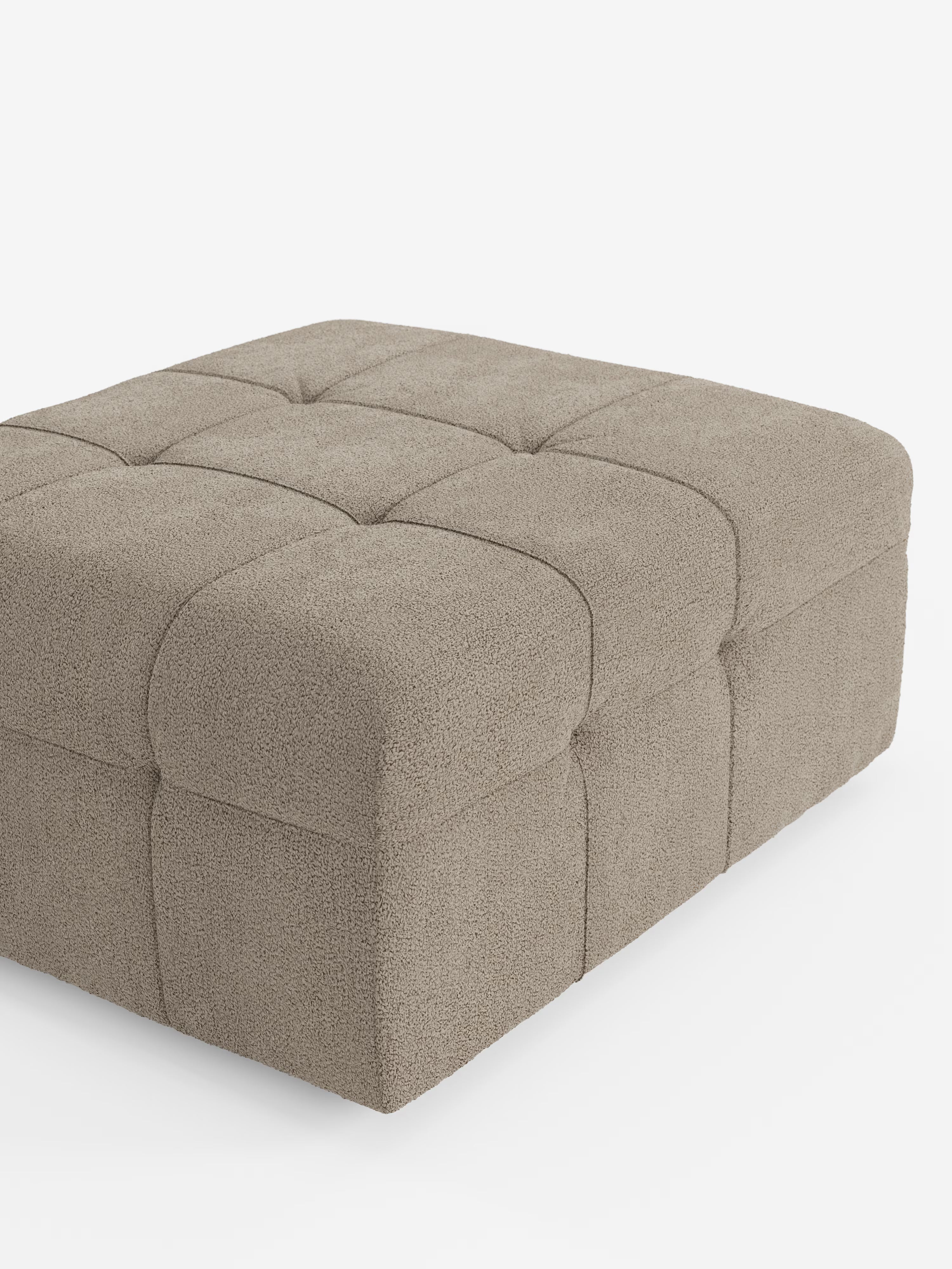 Un pouf quadrato beige di Divani.Store, il modello Mosaic in bouclé (96x77 cm), presenta un morbido e accogliente motivo capitonné a griglia realizzato in tessuto T21 resistente alle macchie. Realizzato in Italia, questo articolo è rivestito in tessuto bouclé lussuosamente morbido con una superficie testurizzata. Il prodotto è raffigurato su uno sfondo bianco, ripreso da un’angolazione frontale parziale a destra.