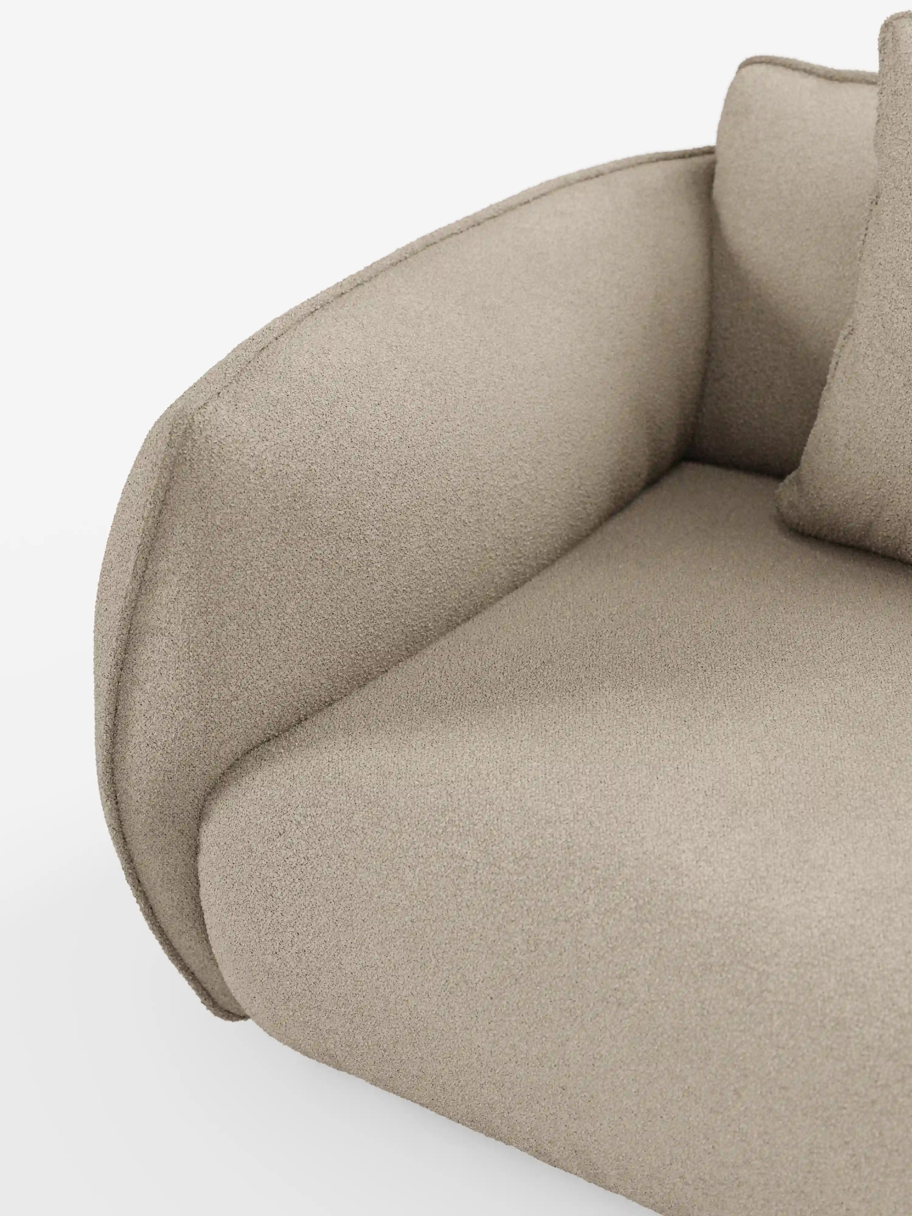 Primo piano del divano modulare a 3 posti “Nimbus” di Divani.Store, realizzato in tessuto T33 beige, con effetto cotone, testurizzato e resistente alle macchie, che mette in risalto il bracciolo ricurvo, il cuscino di seduta e parte del cuscino dello schienale. Il design minimalista e moderno è caratterizzato da linee pulite, con uno sfondo bianco a tinta unita che mette in risalto la silhouette e il materiale del divano.