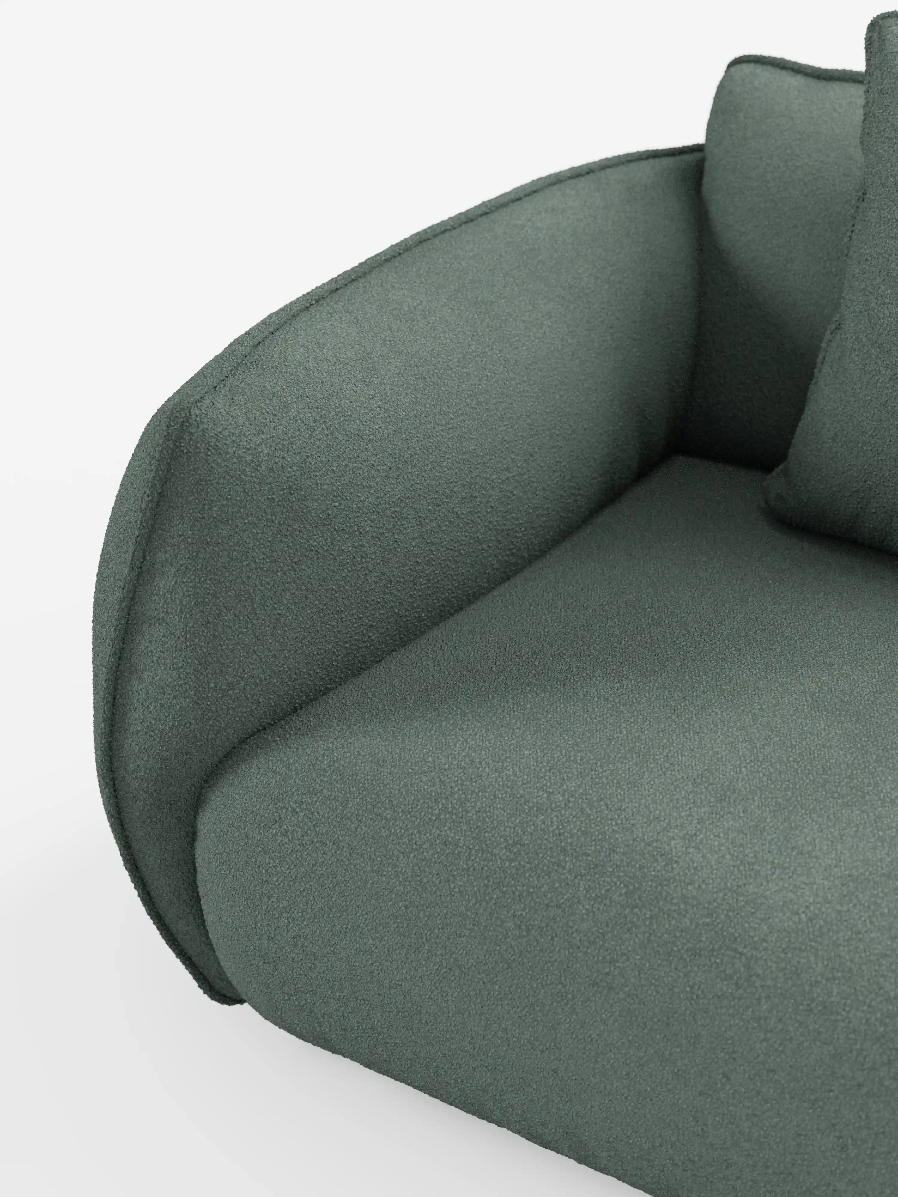 Primo piano del bracciolo e del cuscino di seduta del divano modulare a 3 posti Nimbus di Divani.Store, rivestito in morbido tessuto T33 effetto cotone, resistente alle macchie, in verde intenso. Il bracciolo dalle linee morbide e un cuscino coordinato sono parzialmente visibili sulla destra, su uno sfondo bianco a tinta unita che conferisce al tutto un’estetica pulita e minimalista.