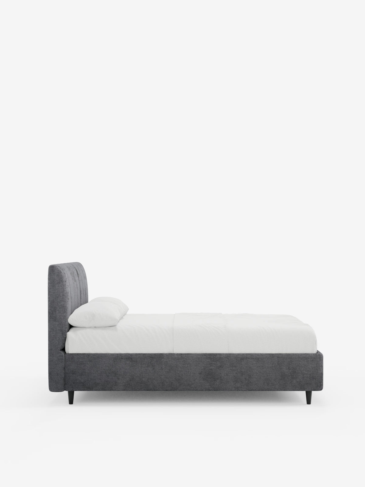 Vista laterale del letto imbottito ONYX con contenitore e testiera verticale in tessuto certificato Oeko-Tex® di Letti.store, caratterizzato da una struttura imbottita di colore grigio scuro e da una testiera con cuciture verticali. Il letto è rivestito con biancheria da letto bianca, con un unico cuscino bianco, e poggia su gambe corte e nere, che risaltano su uno sfondo bianco a tinta unita.