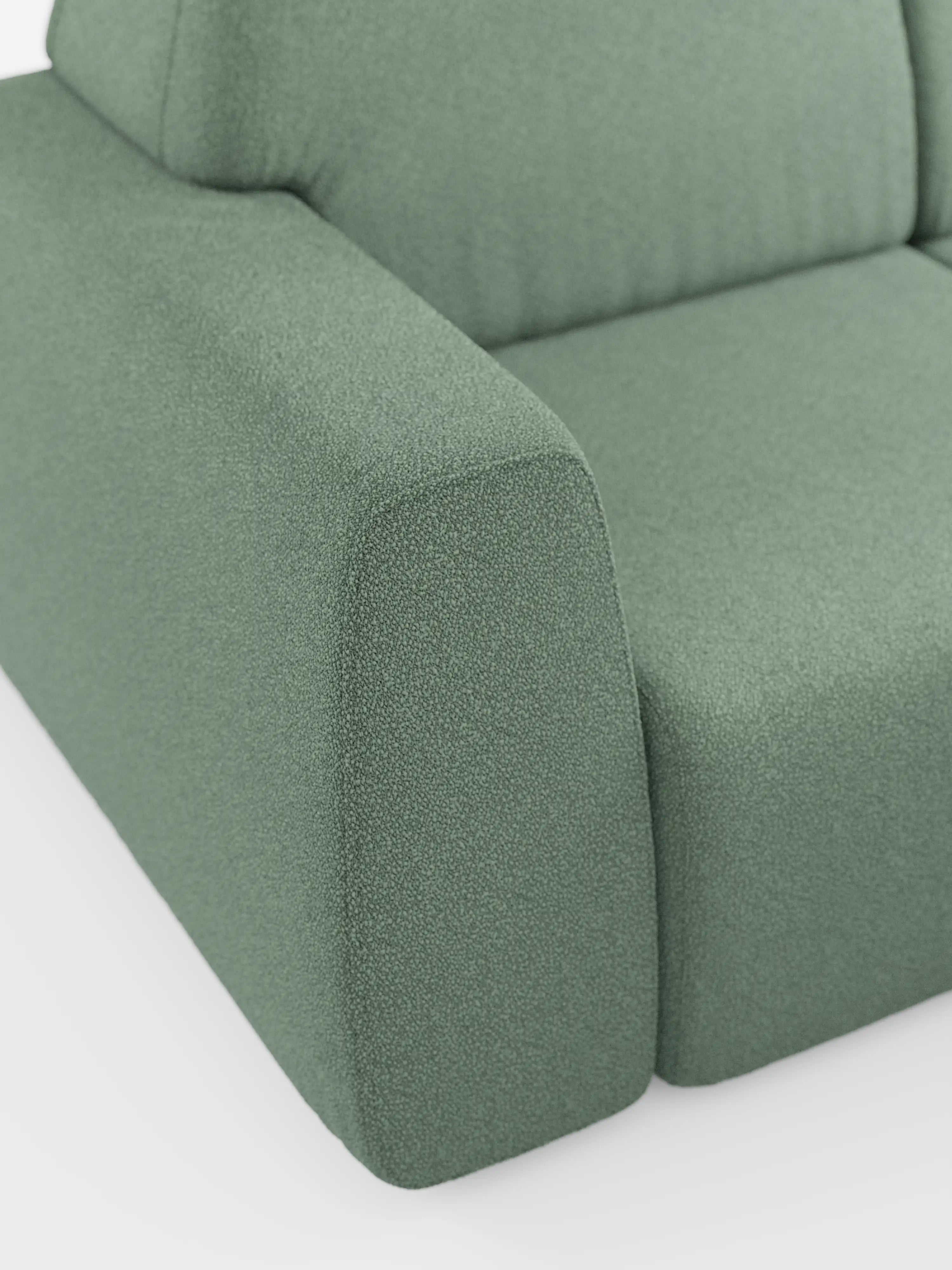 Primo piano del bracciolo sinistro e di una parte della seduta del divano Orbit con 3 sedute scorrevoli e allungabili in tessuto effetto cotone smacchiabile T33 di Divani.Store. Questo divano moderno si caratterizza per le linee pulite e un ampio bracciolo rettangolare, rivestito in tessuto testurizzato di un verde tenue che ne esalta il design contemporaneo. Lo sfondo bianco e il pavimento in tinta unita mettono in risalto il colore e il materiale di alta qualità del divano.