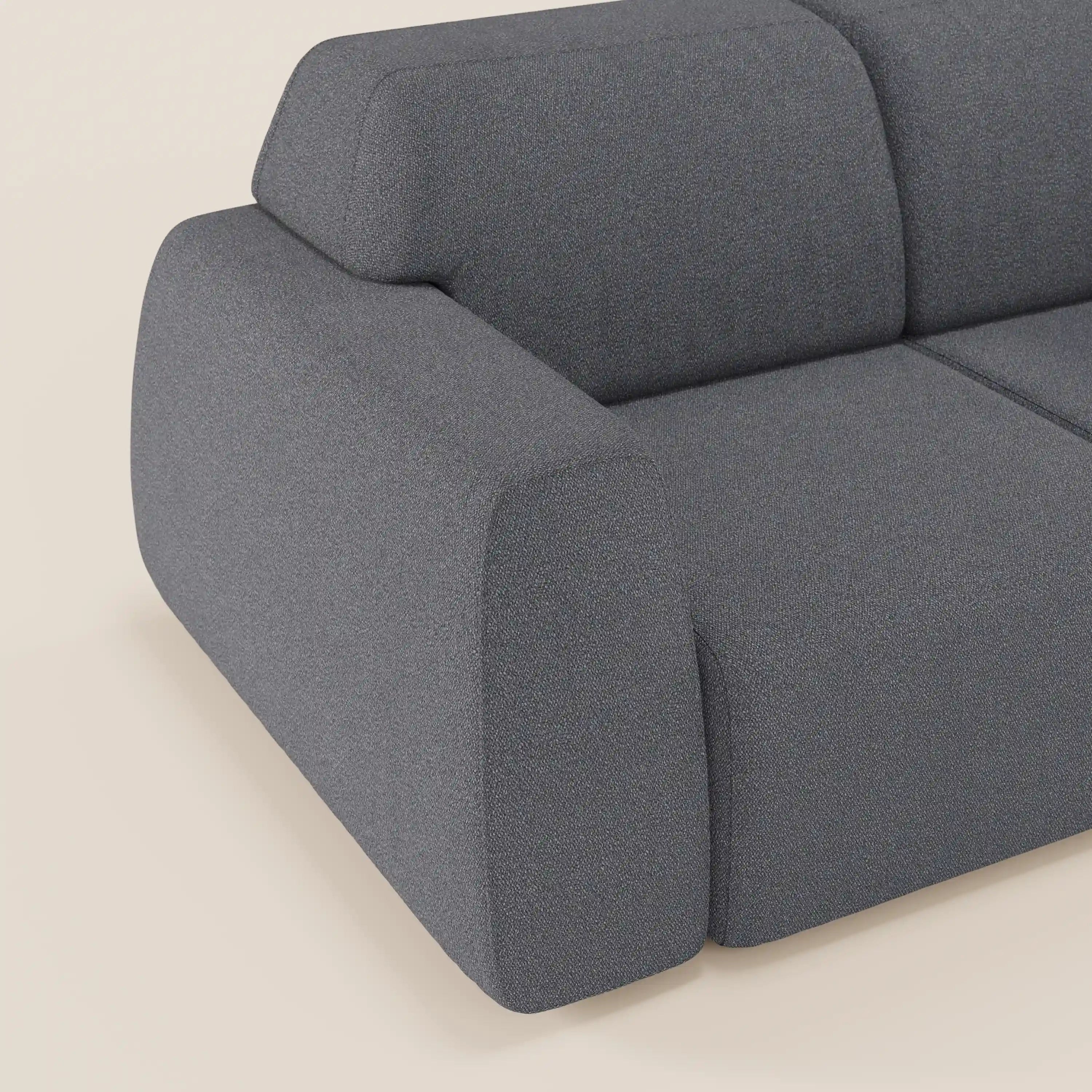 Un primo piano del divano Orbit 2 e 3 posti di Divani.Store, in tessuto smacchiabile effetto cotone T33 grigio scuro, con braccioli arrotondati e sedute scorrevoli. Il design minimalista poggia su un pavimento beige chiaro, valorizzato da luci soffuse.